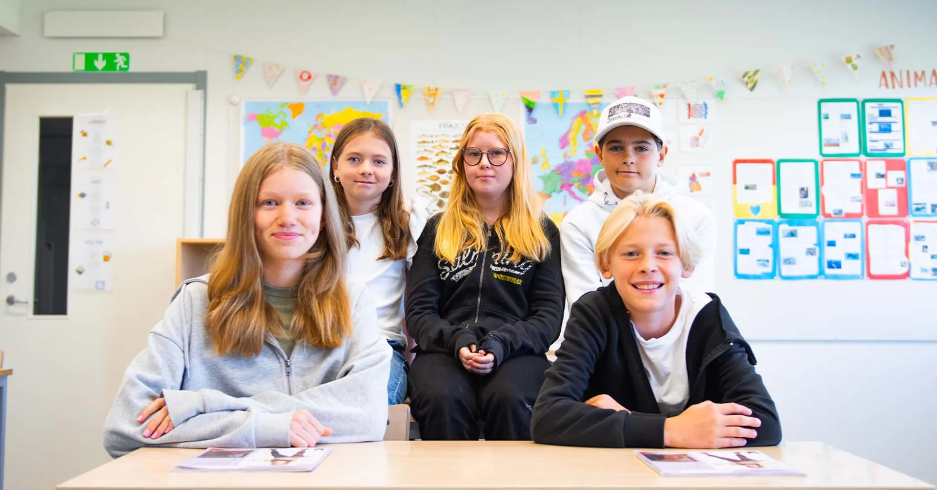 Fem elever i ett klassrum med newbody kataloger framför sig