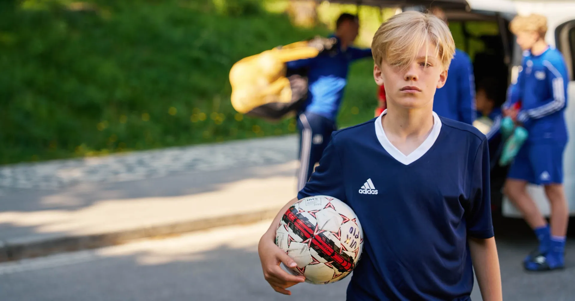 Fotbollkille ensam med en boll i handen framför en minibuss.