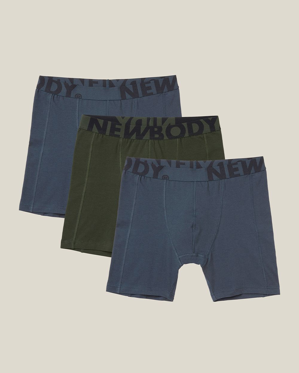 Tre mjuka långboxers i gröna och blå nyanser med resårband som har tryckta bokstäver. Enkel och bekväm design för vardagsbruk.