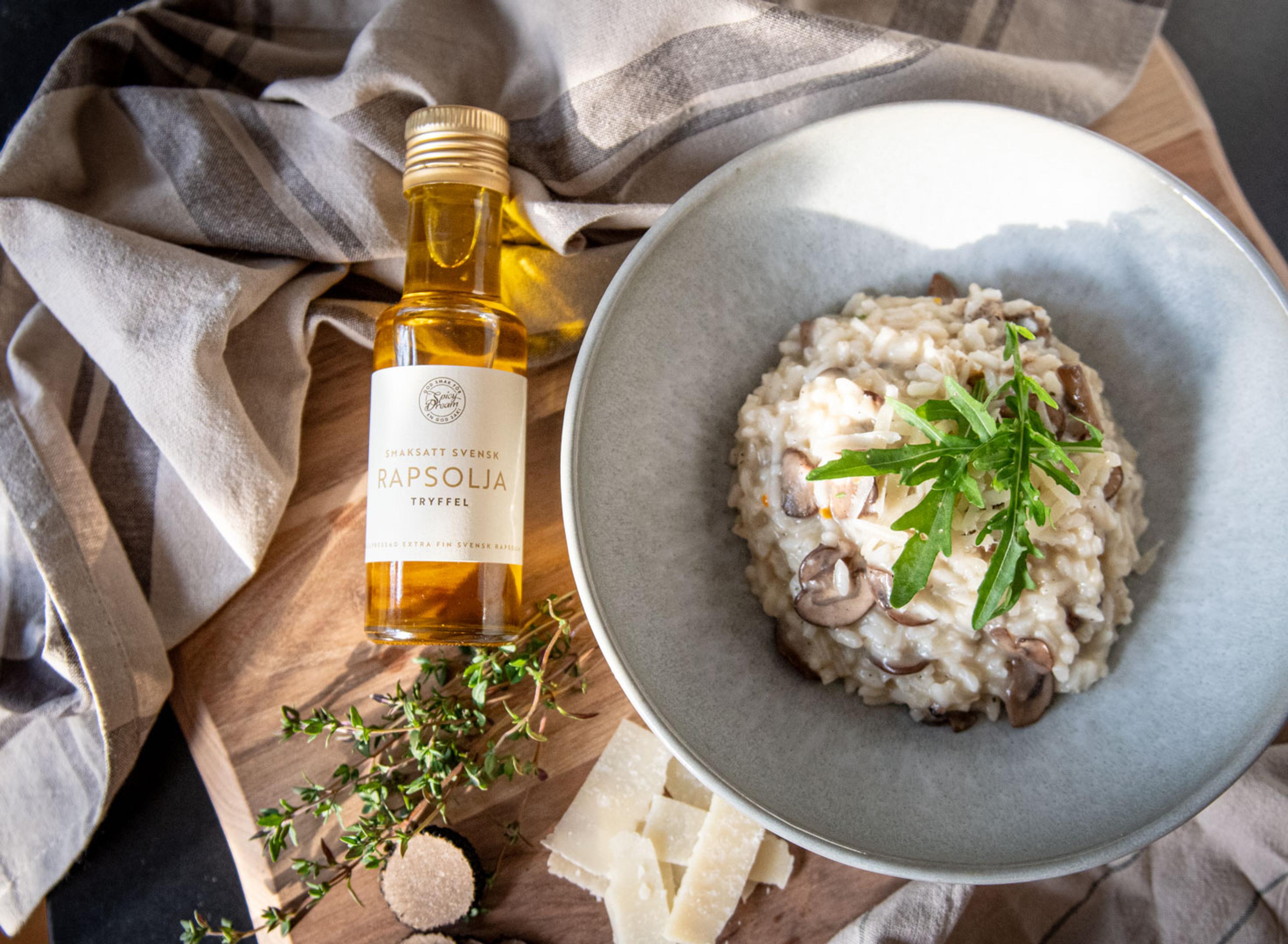 En glasflaska smaksatt rapsolja med smak av tryffel bredvid en tallrik krämig svamprisotto