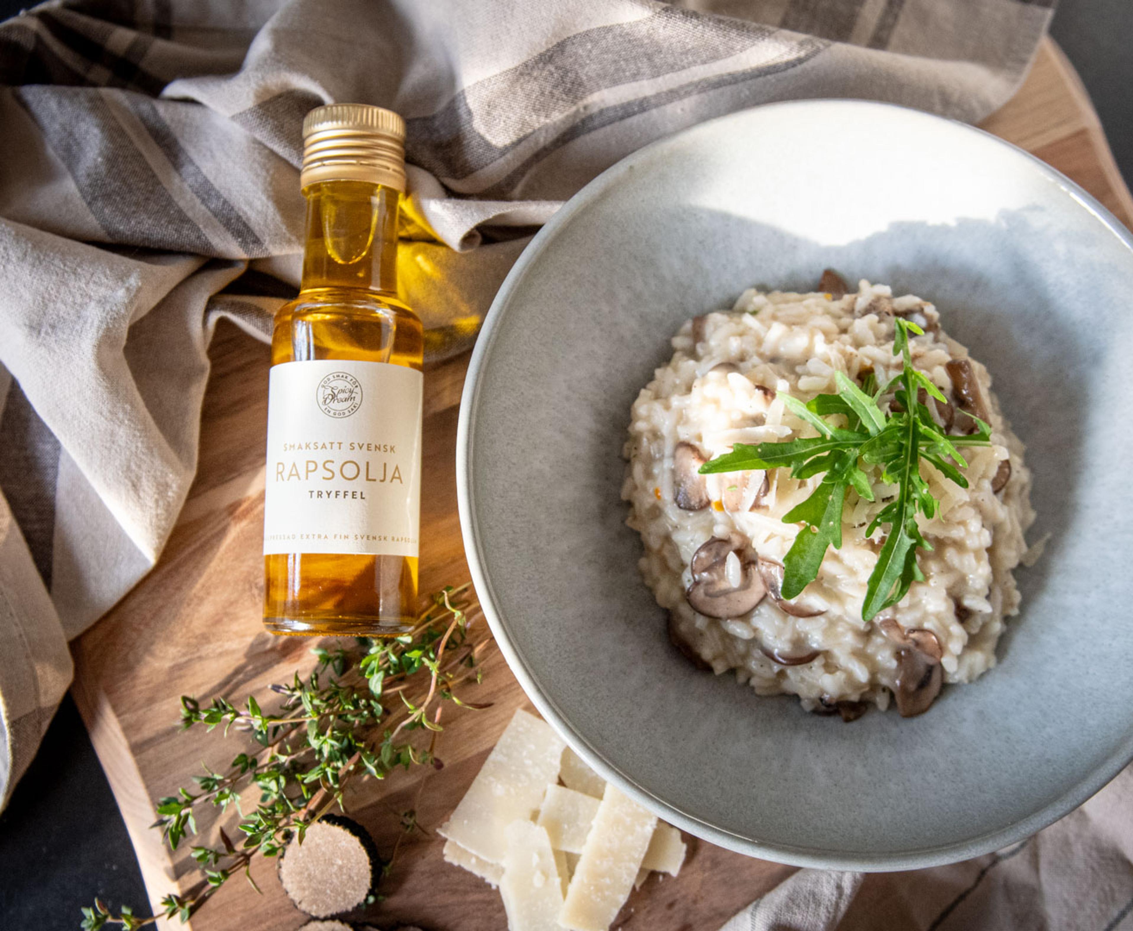 En glasflaska smaksatt rapsolja med smak av tryffel bredvid en tallrik krämig svamprisotto