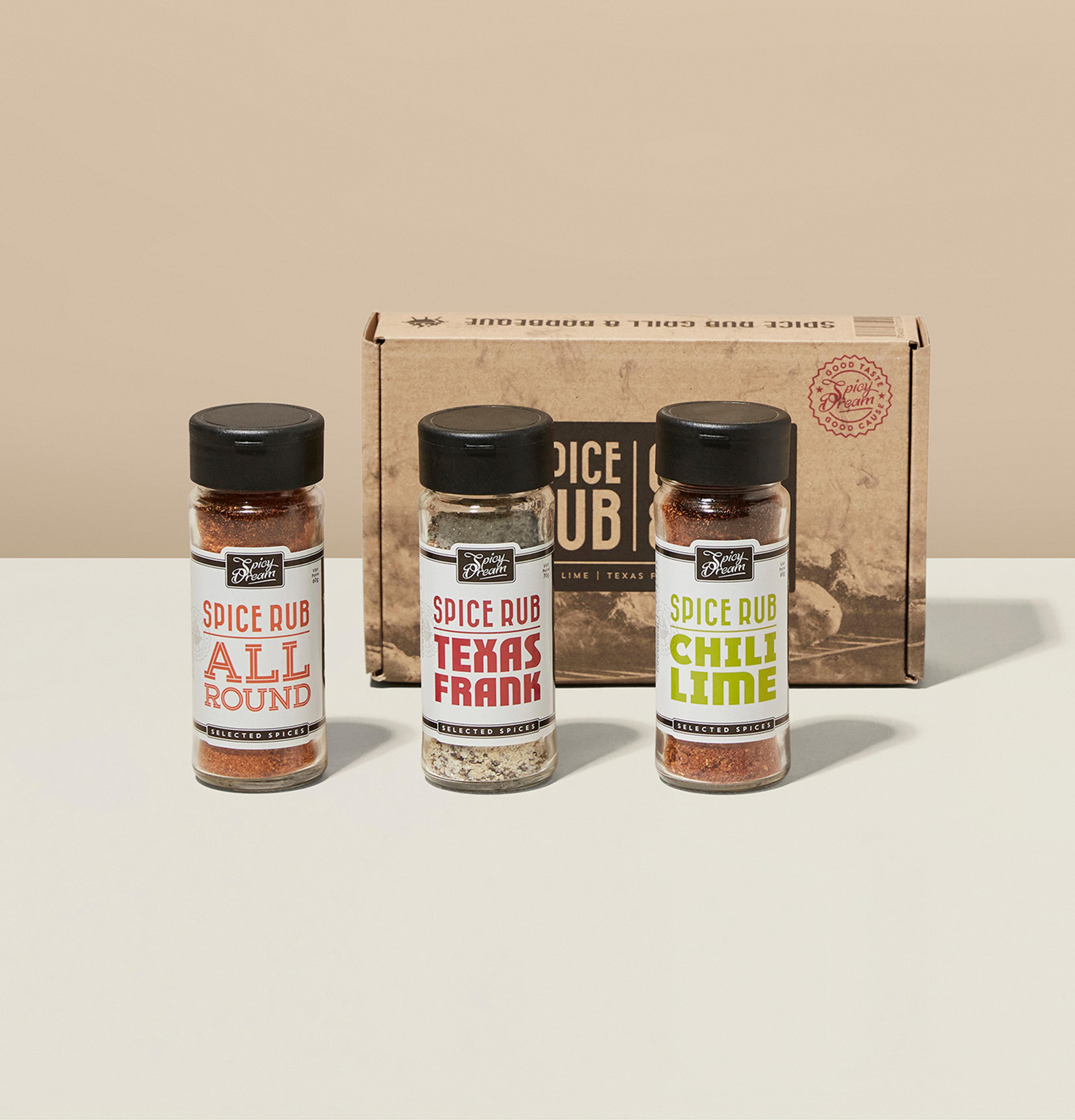 Tre små kryddburkar med spice rub i smakerna allround, texas frank och chili lime, framför en beige kartong.