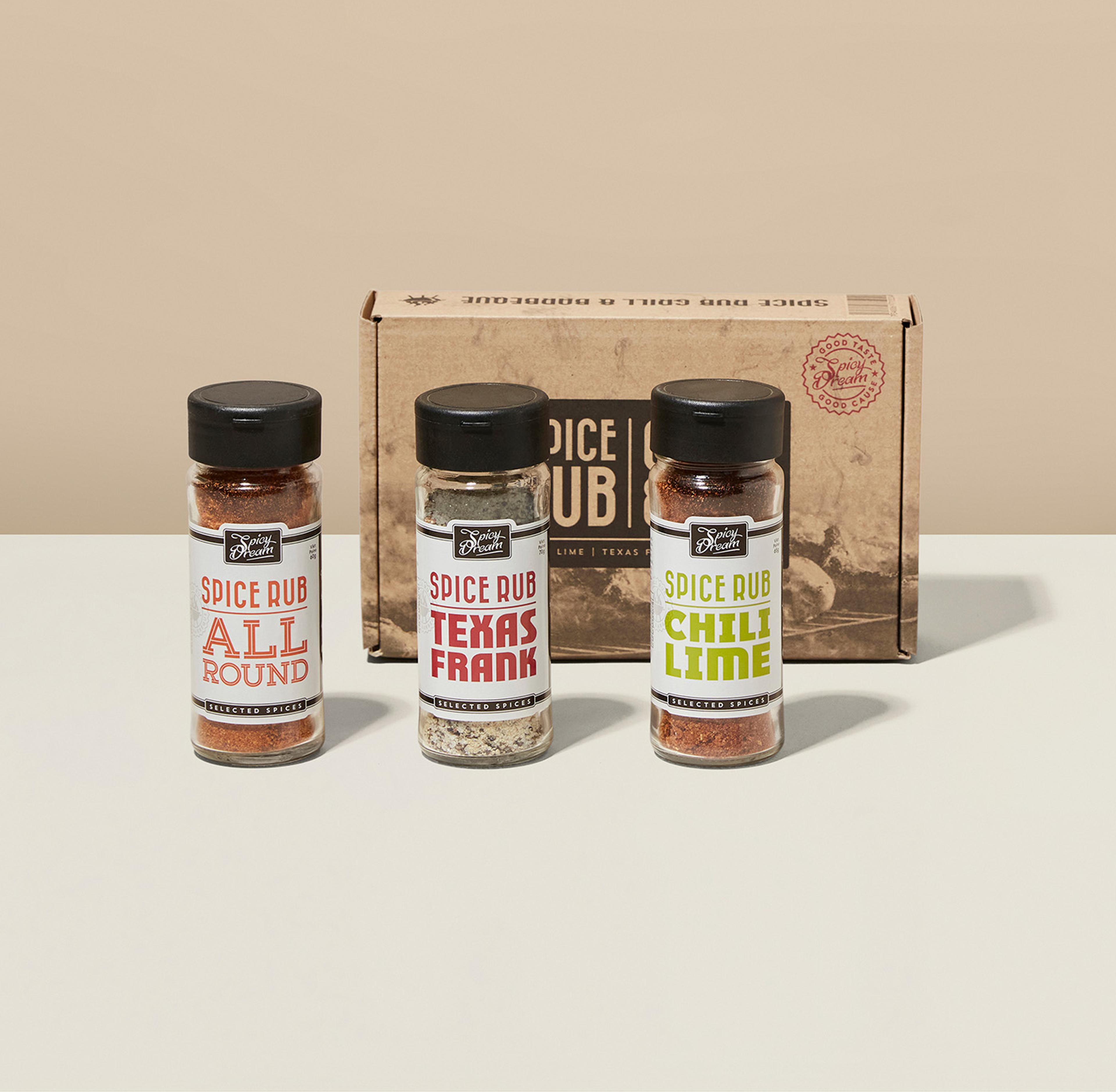 Tre små kryddburkar med spice rub i smakerna allround, texas frank och chili lime, framför en beige kartong.
