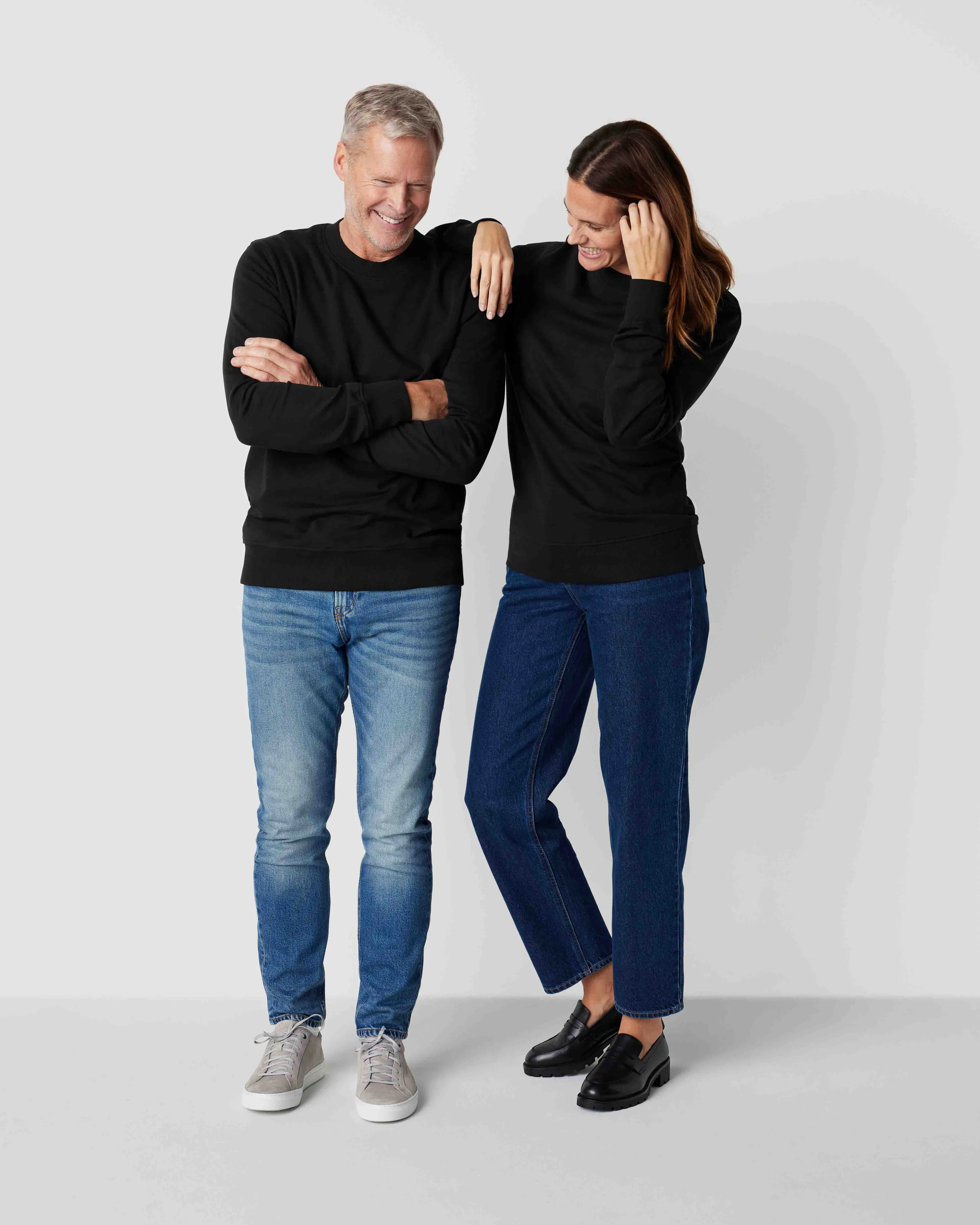 Svarta sweatshirts i enkel, klassisk design, bärs av en man och en kvinna med jeans. Sweatshirtsen har ribbstickade ärmslut och fåll.