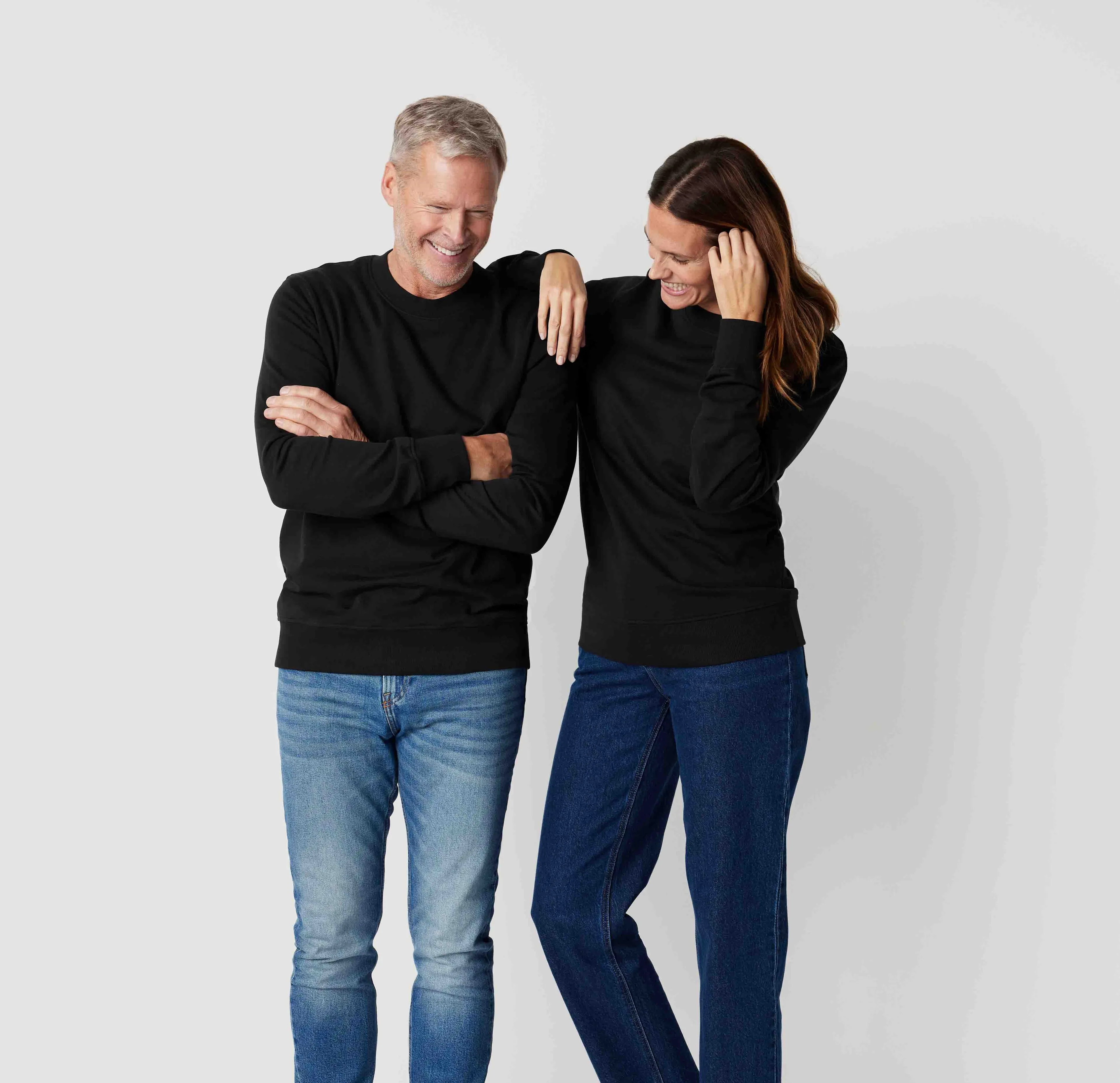 Svarta sweatshirts i enkel, klassisk design, bärs av en man och en kvinna med jeans. Sweatshirtsen har ribbstickade ärmslut och fåll.