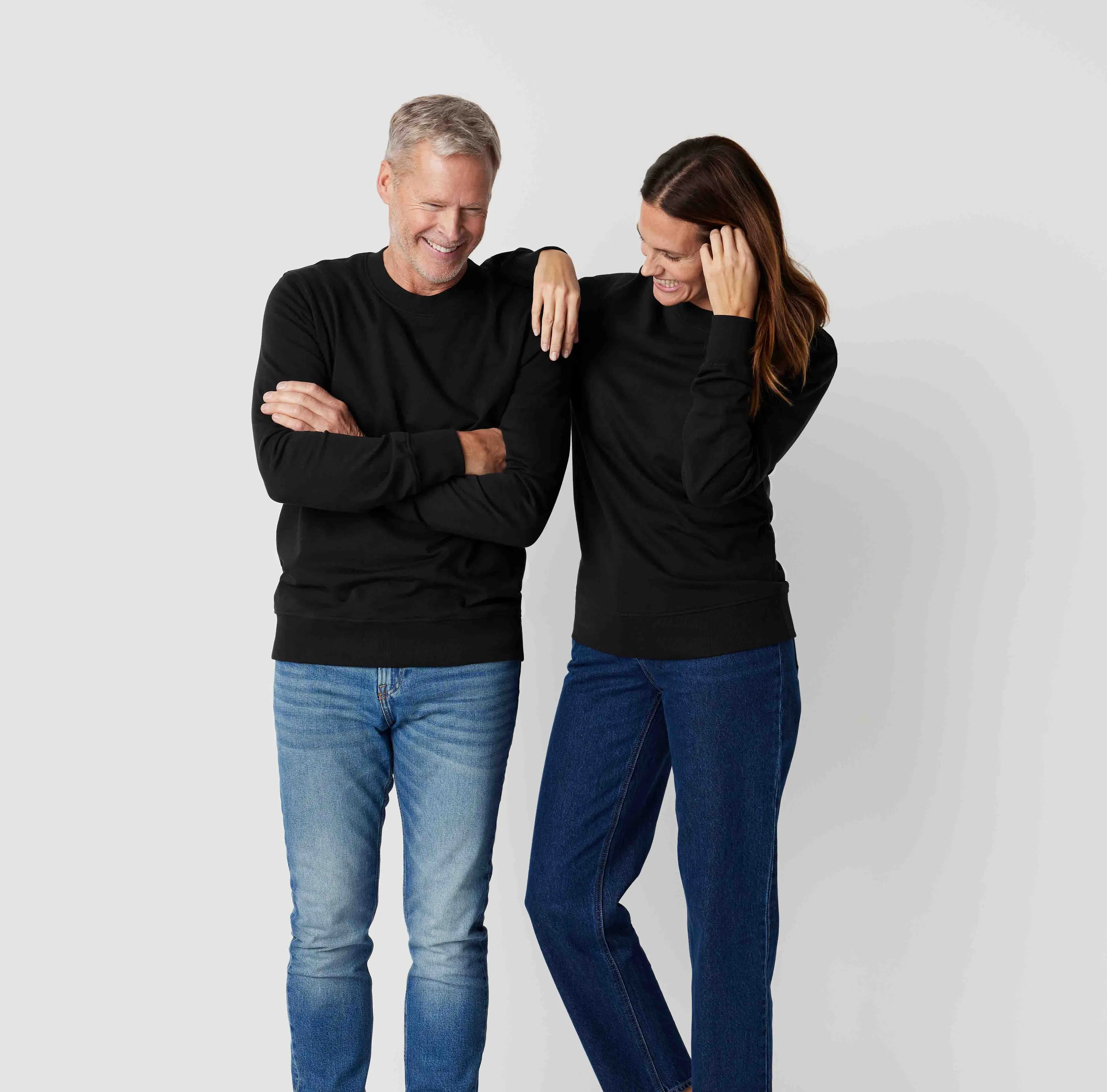 Svarta sweatshirts i enkel, klassisk design, bärs av en man och en kvinna med jeans. Sweatshirtsen har ribbstickade ärmslut och fåll.