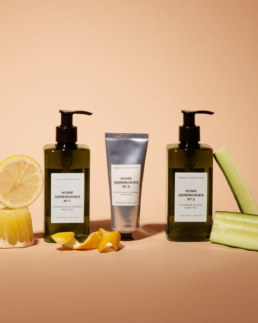 Två pumpflaskor med handtvål i dofterna lemongrass & verbena samt cucumber & mint, tillsammans med en tub handkräm i lemongrass & verbena. Produkten omges av citrusskal och gurkskivor som visar doft