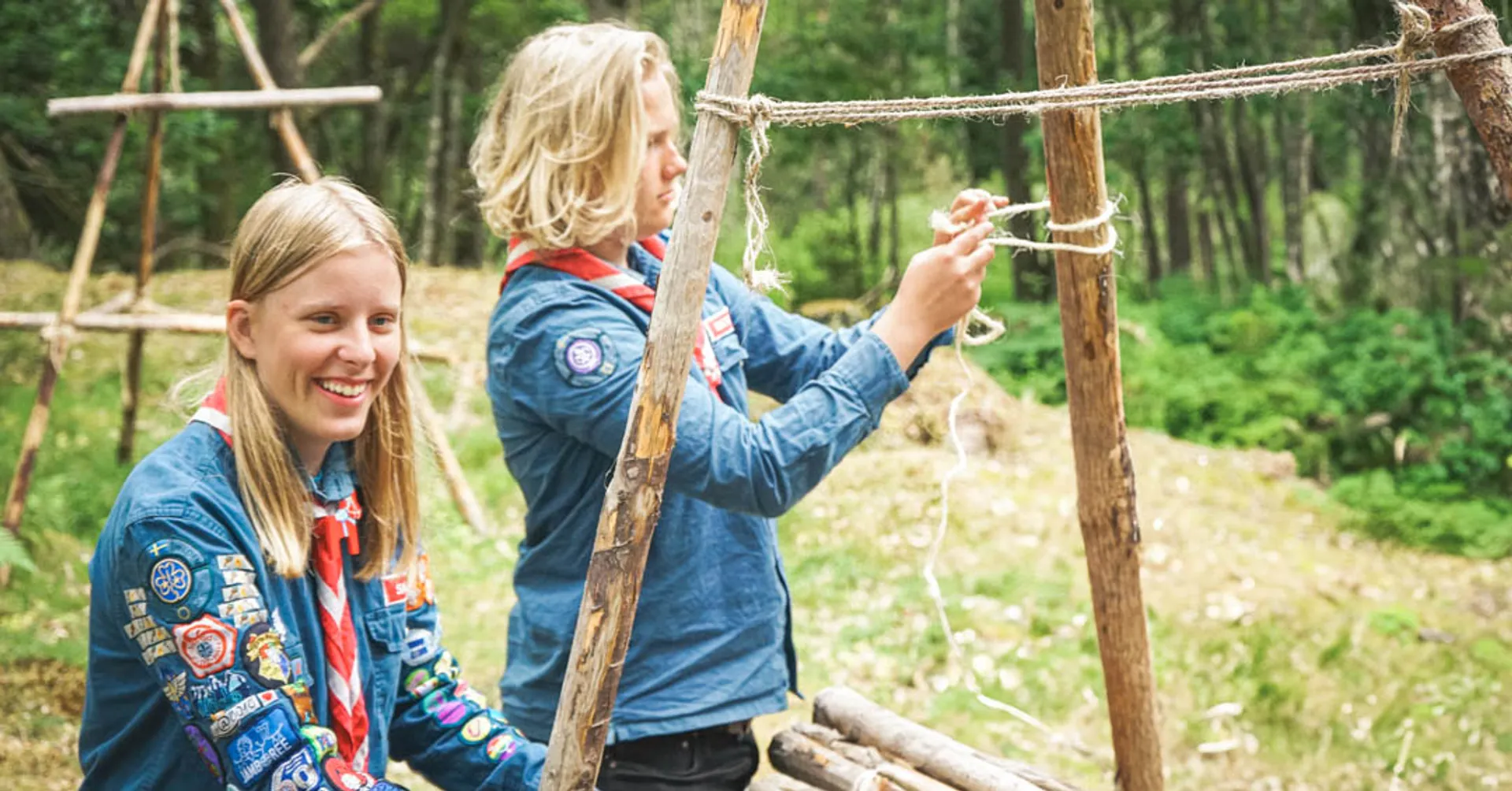 Två scoutungdomar binder knopar i skogen