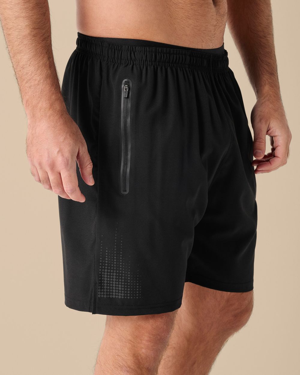 Svarta träningsshorts med resår i midjan och blixtlåsförsedd ficka på sidan. Shortsen har diskreta prickmönster i nedre kanten för en modern touch.