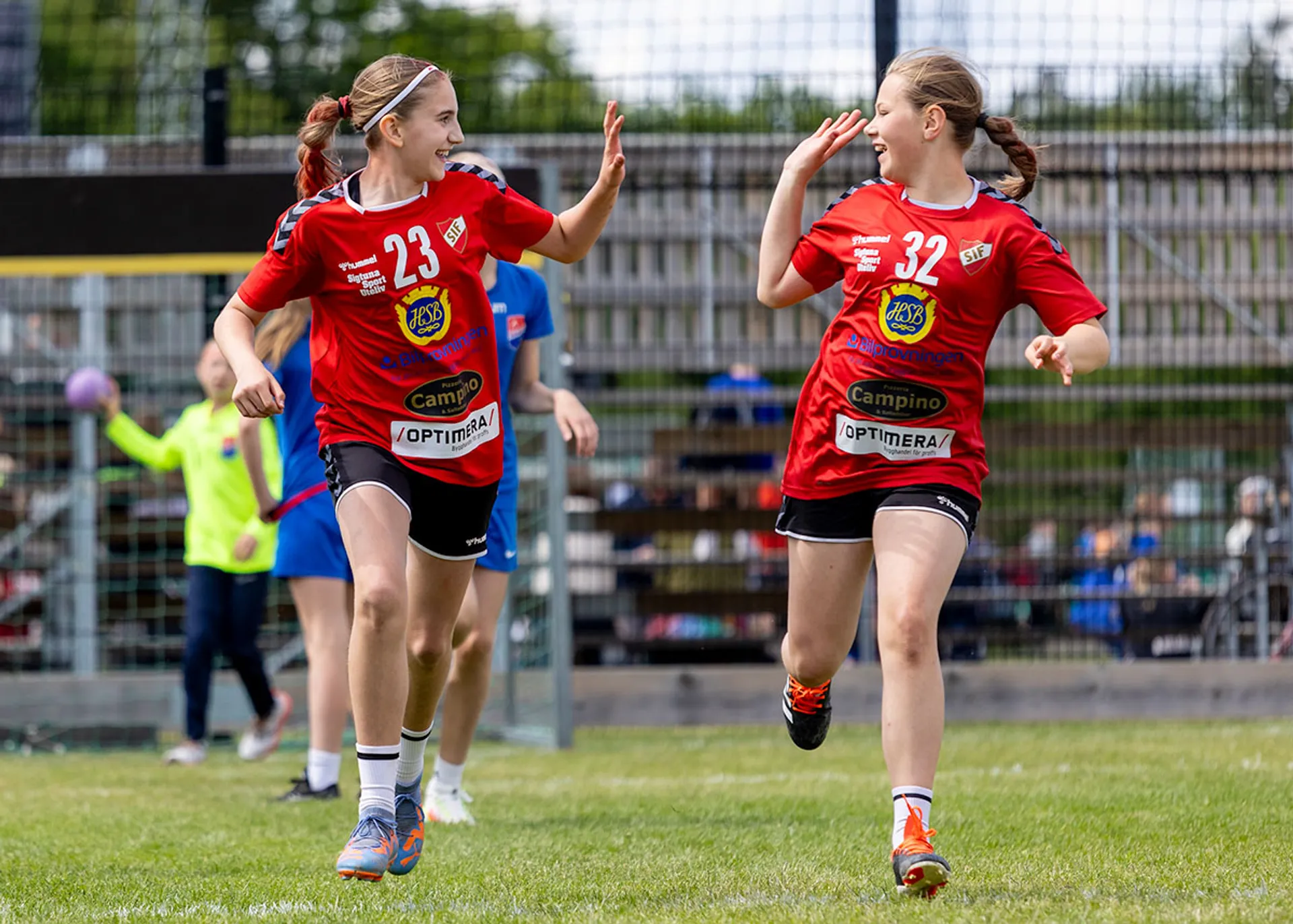 Handbollstjejer springer över planen och gör en high five.
