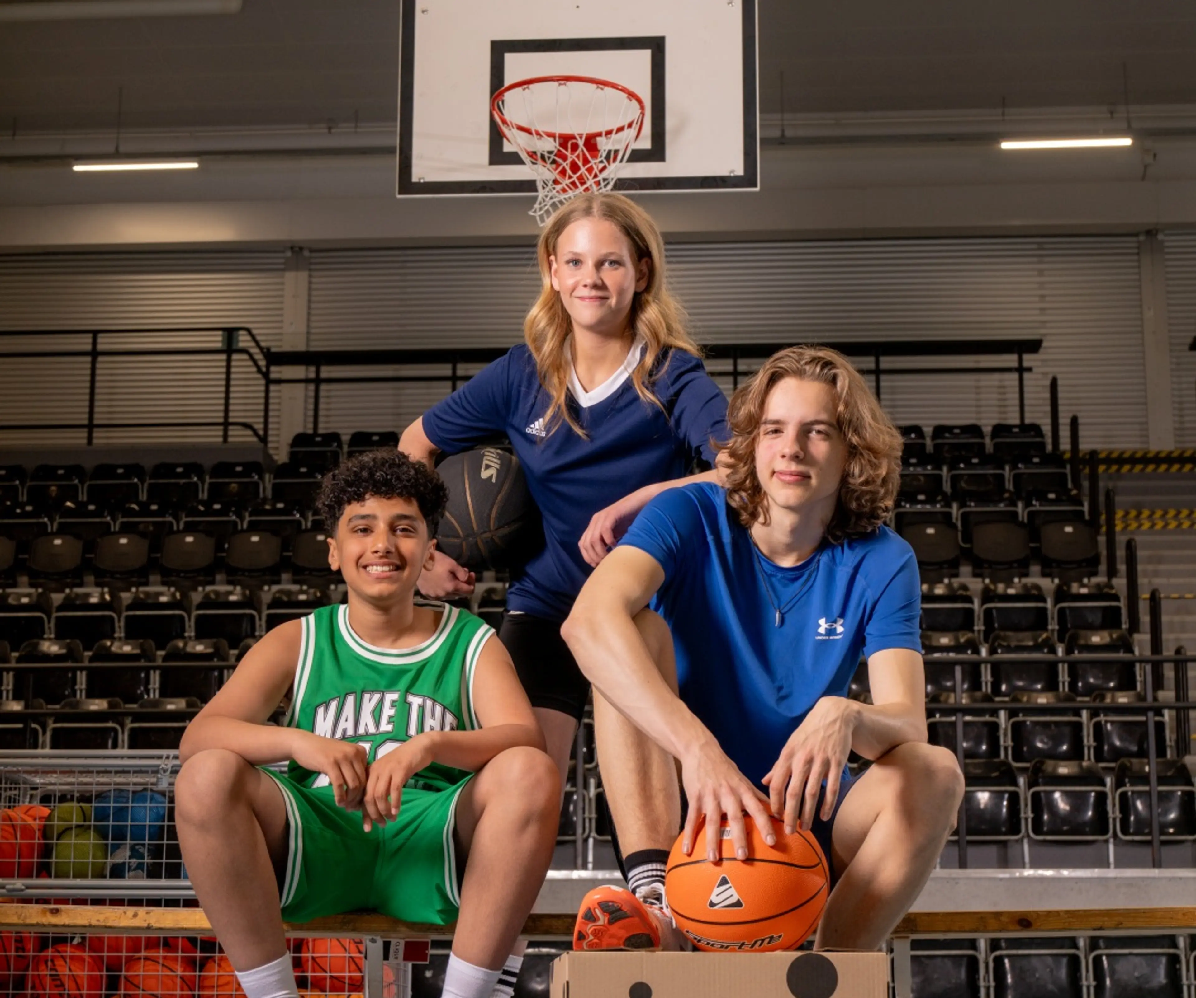 Tre basketspelare med en basketboll och en Newbody kartong
