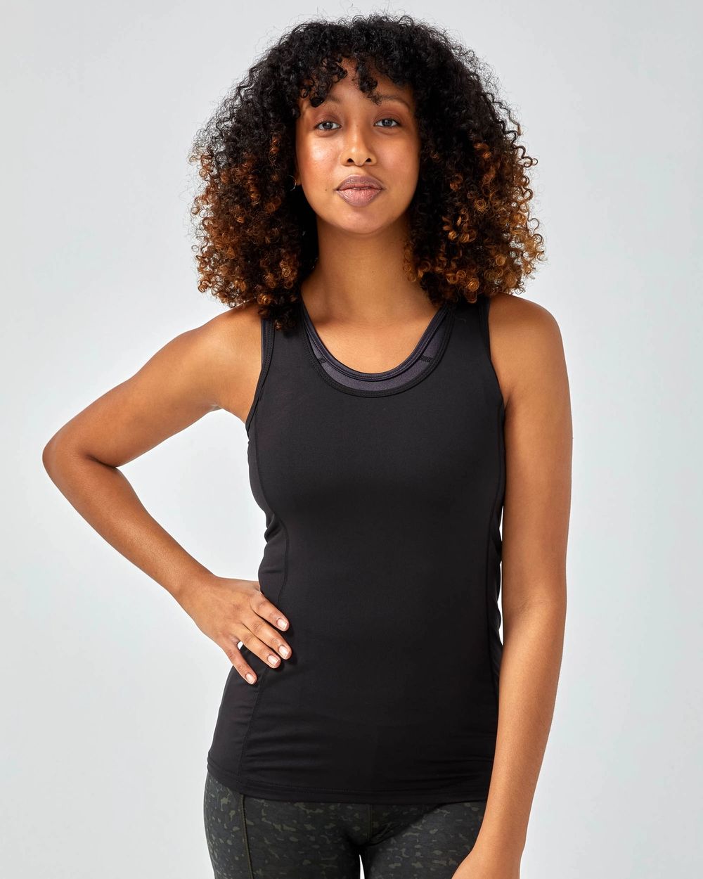 Svart sportlinne i smal passform med rund halsringning, bärs med ett matchande sport-BH under. Enkel och funktionell design för aktiv användning.