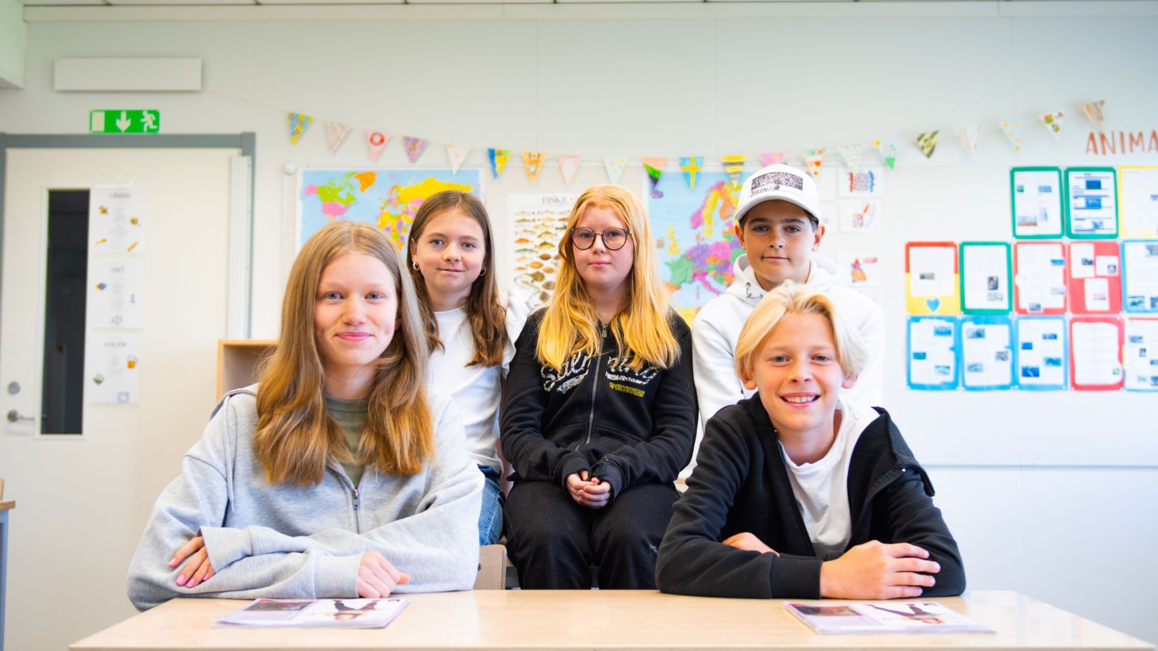 Fem elever som sitter i sitt klassrum med newbody kataloger