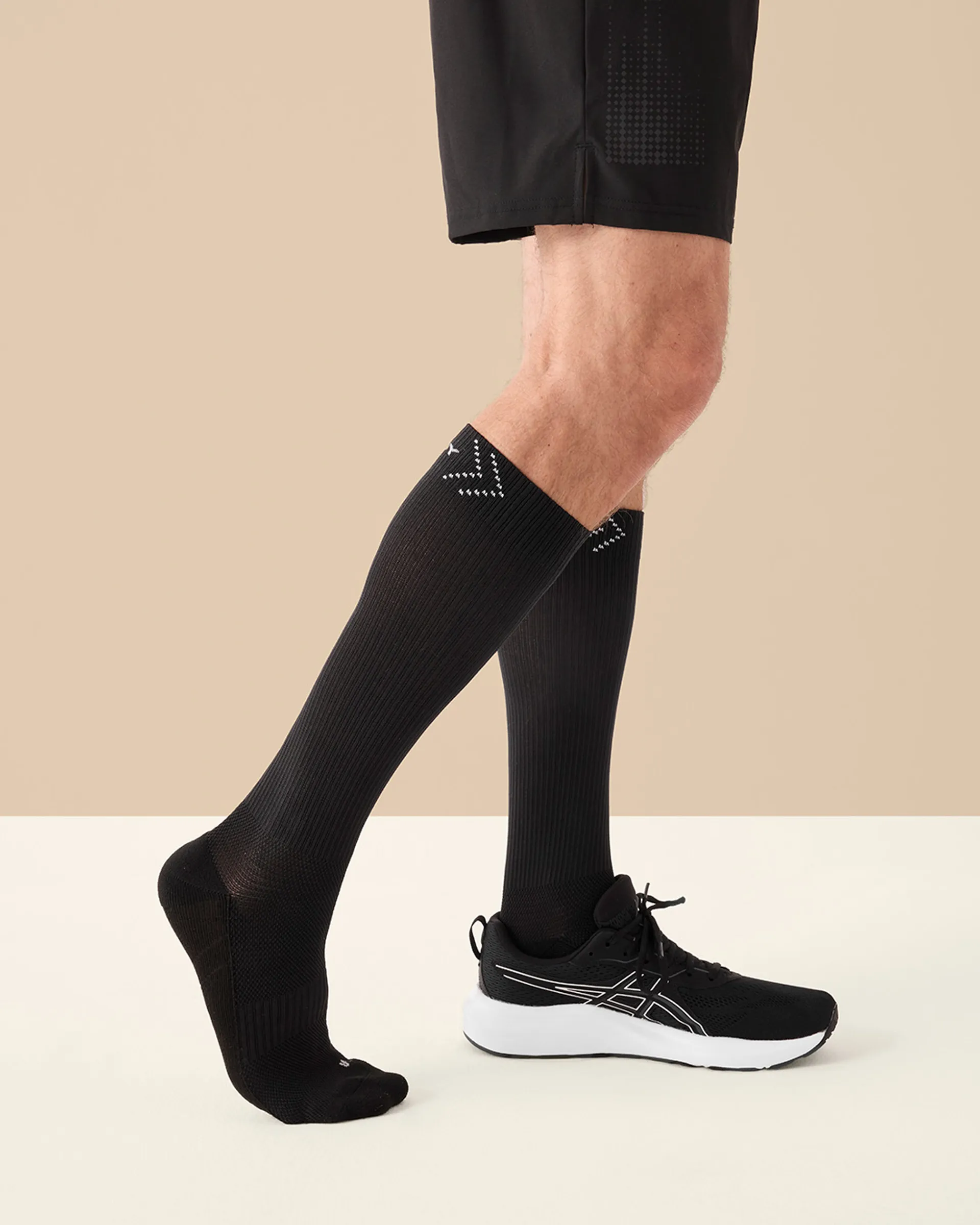 Manlig modell bär svarta High Performance Socks med högt skaft, visad från sidan