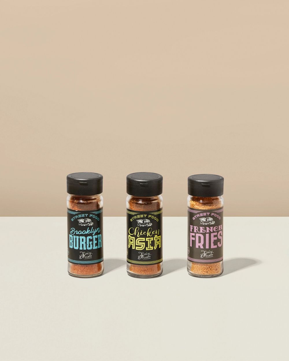 Tre kryddburkar med svart lock, märkta Brooklyn Burger, Chicken Asia och French Fries, med olika färgglada etiketter och innehåll i rött till brunt.