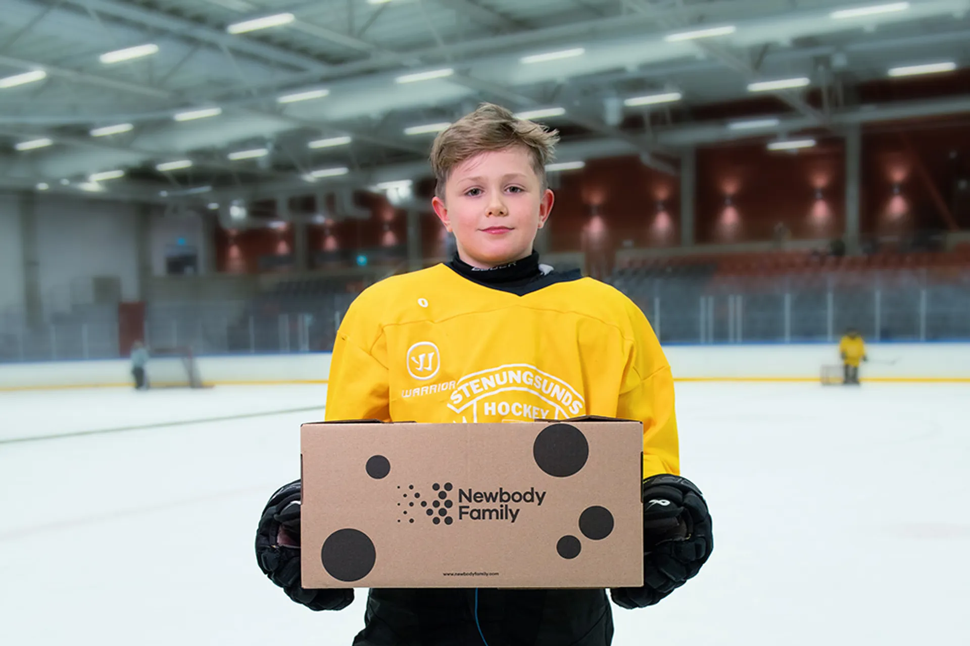 Hockeyspelare står på isen och håller en newbody kartong