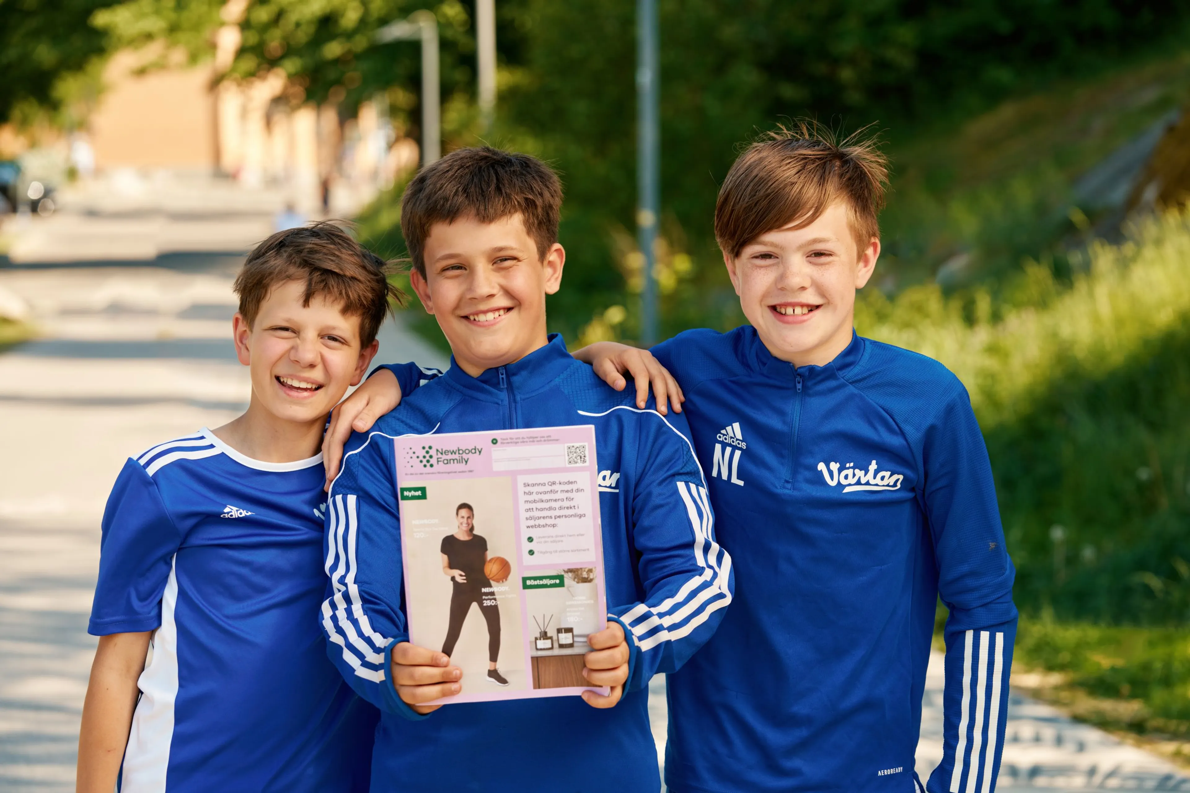 Tre pojkar som bär blå träningsoveraller och har en newbody katalog