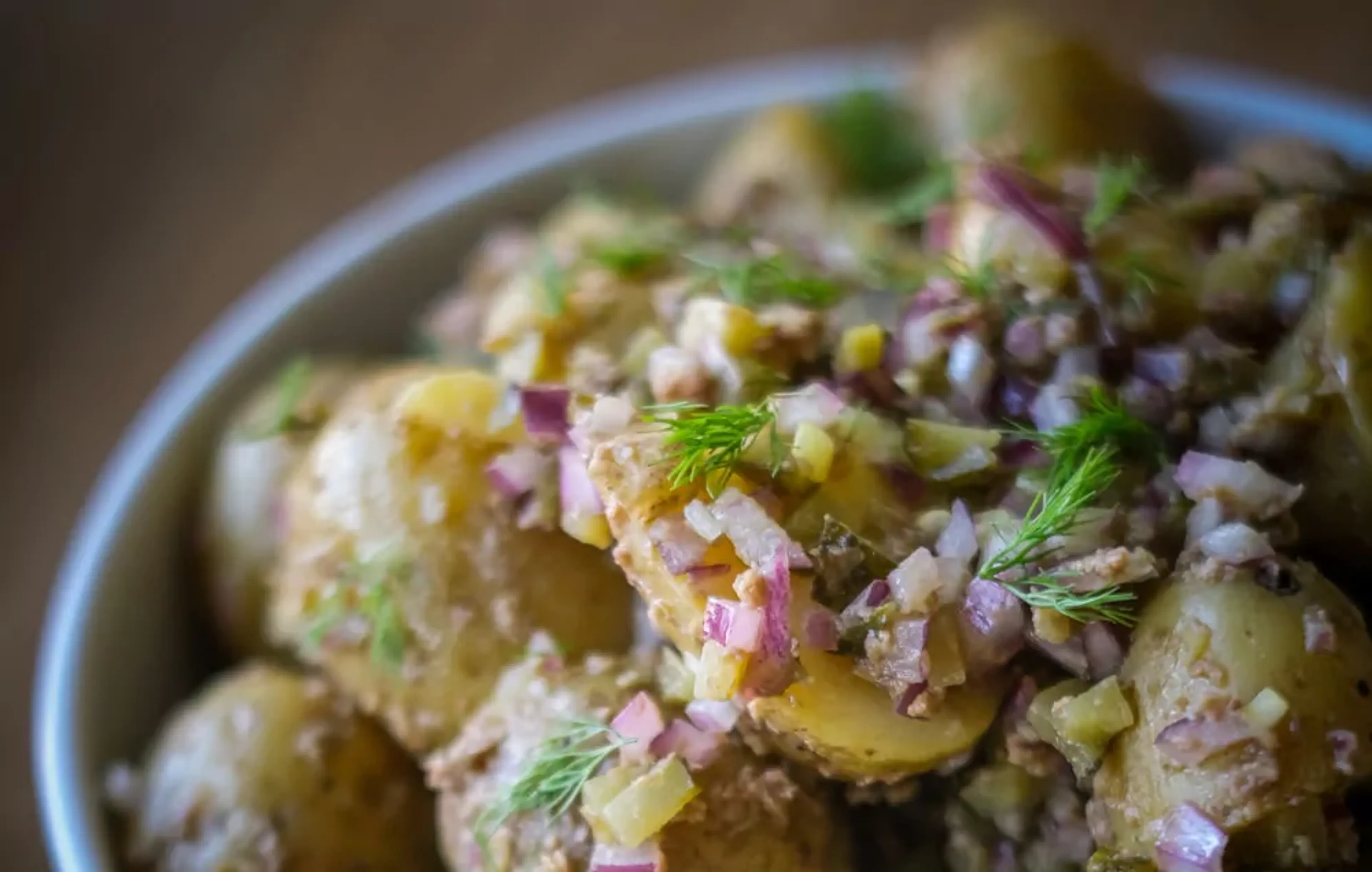 Potatissallad med små, skalade delikatesspotatisar blandade med finhackad rödlök och dill. En enkel och fräsch sommarrätt.