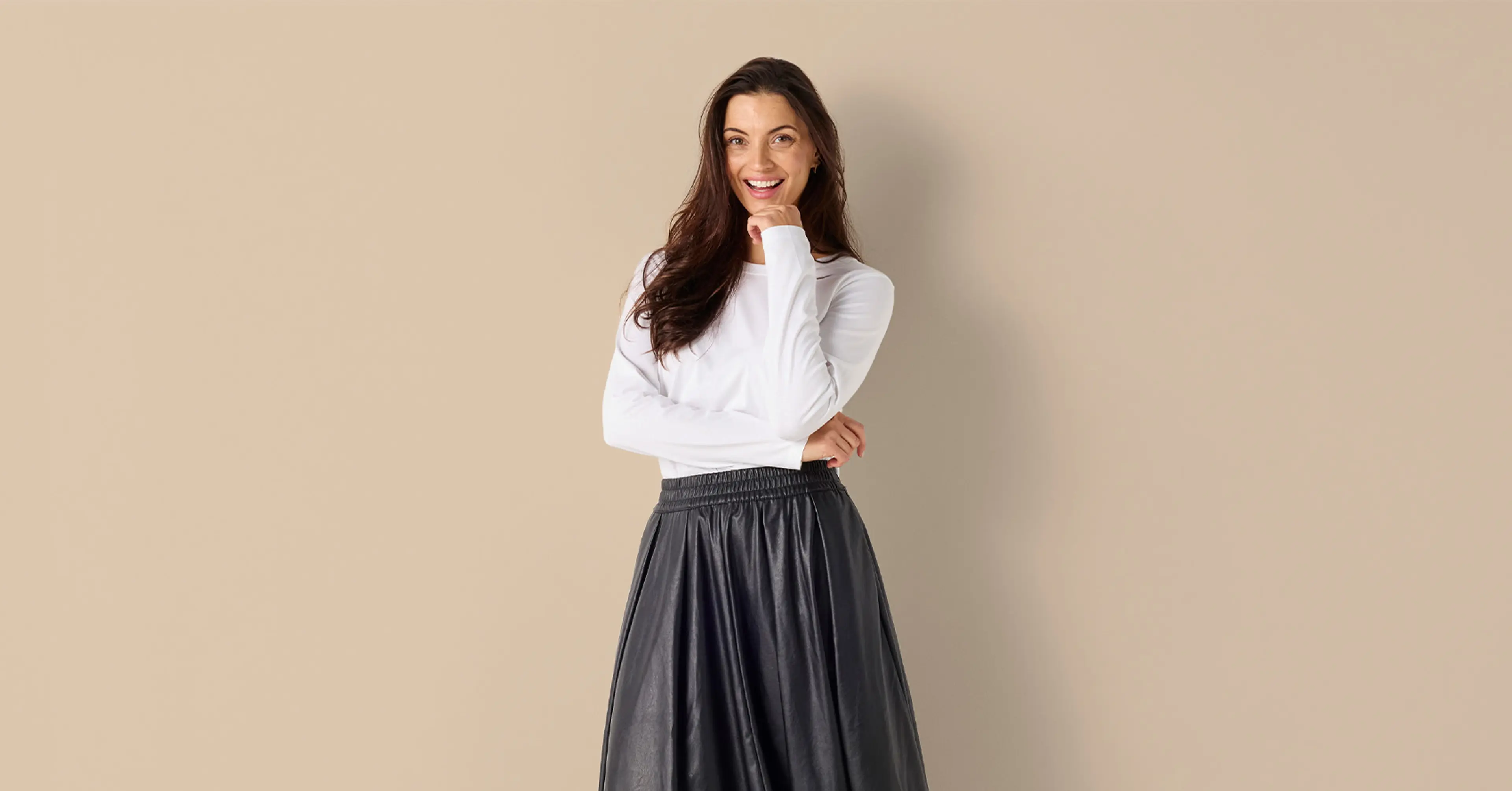 Vit långärmad damtop i mjuk bomull tillsammans med en lång svart skinn kjol och svarta loafers