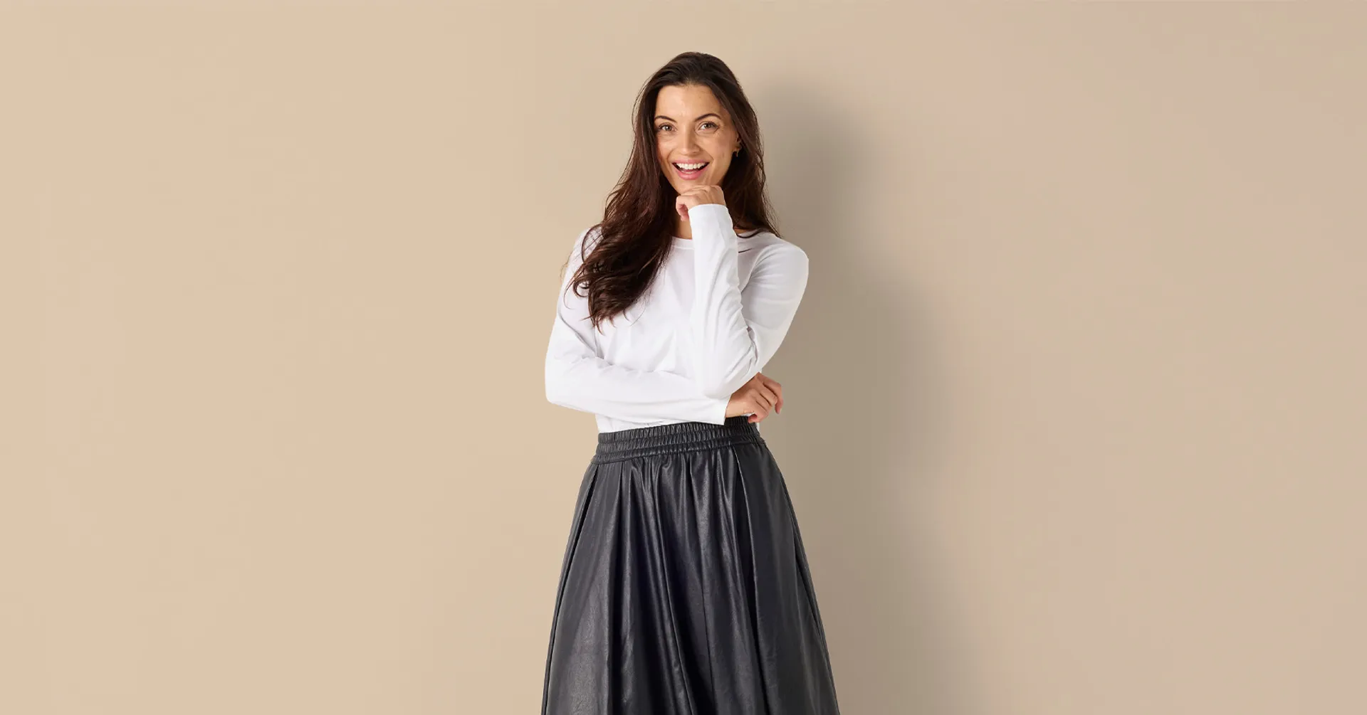 Vit långärmad damtop i mjuk bomull tillsammans med en lång svart skinn kjol och svarta loafers