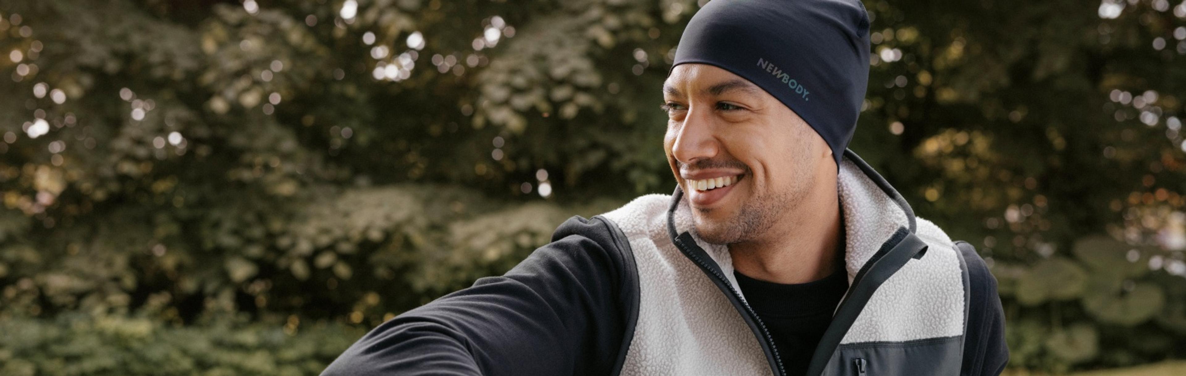 Man i mjuk beige pile vest med gröna detaljer, han sitter på en gräsmatta