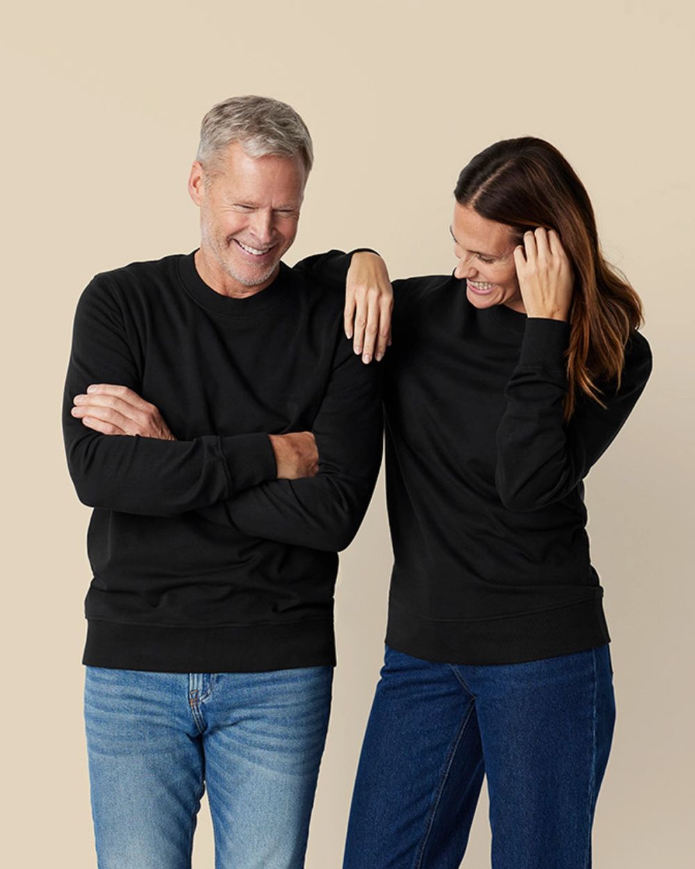 Svart sweatshirt i enkel, klassisk design, modell unisex för både herr och dam. Modellerna bär den tillsammans med jeans.