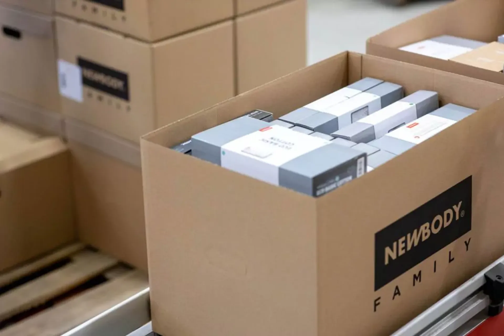 En öppen kartong fylld med prydligt paketerade produkter i olika storlekar, redo för leverans. Kartongen står på en pall tillsammans med andra liknande lådor.