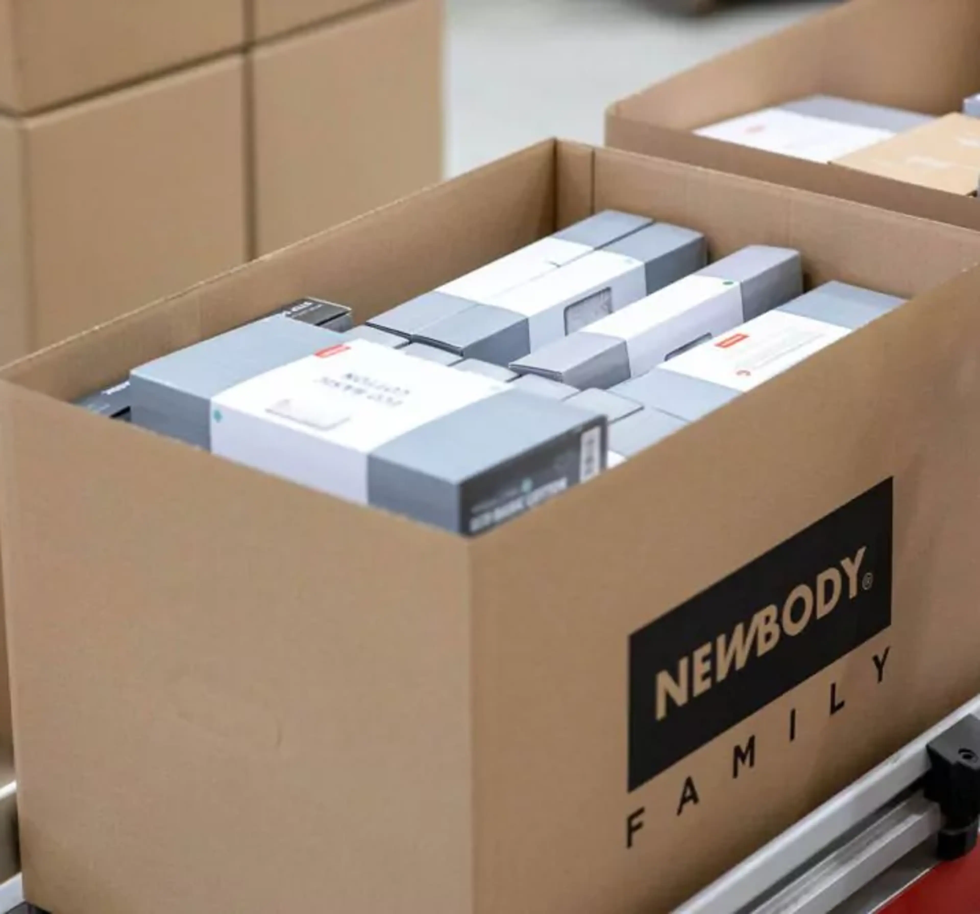 En öppen kartong fylld med prydligt paketerade produkter i olika storlekar, redo för leverans. Kartongen står på en pall tillsammans med andra liknande lådor.