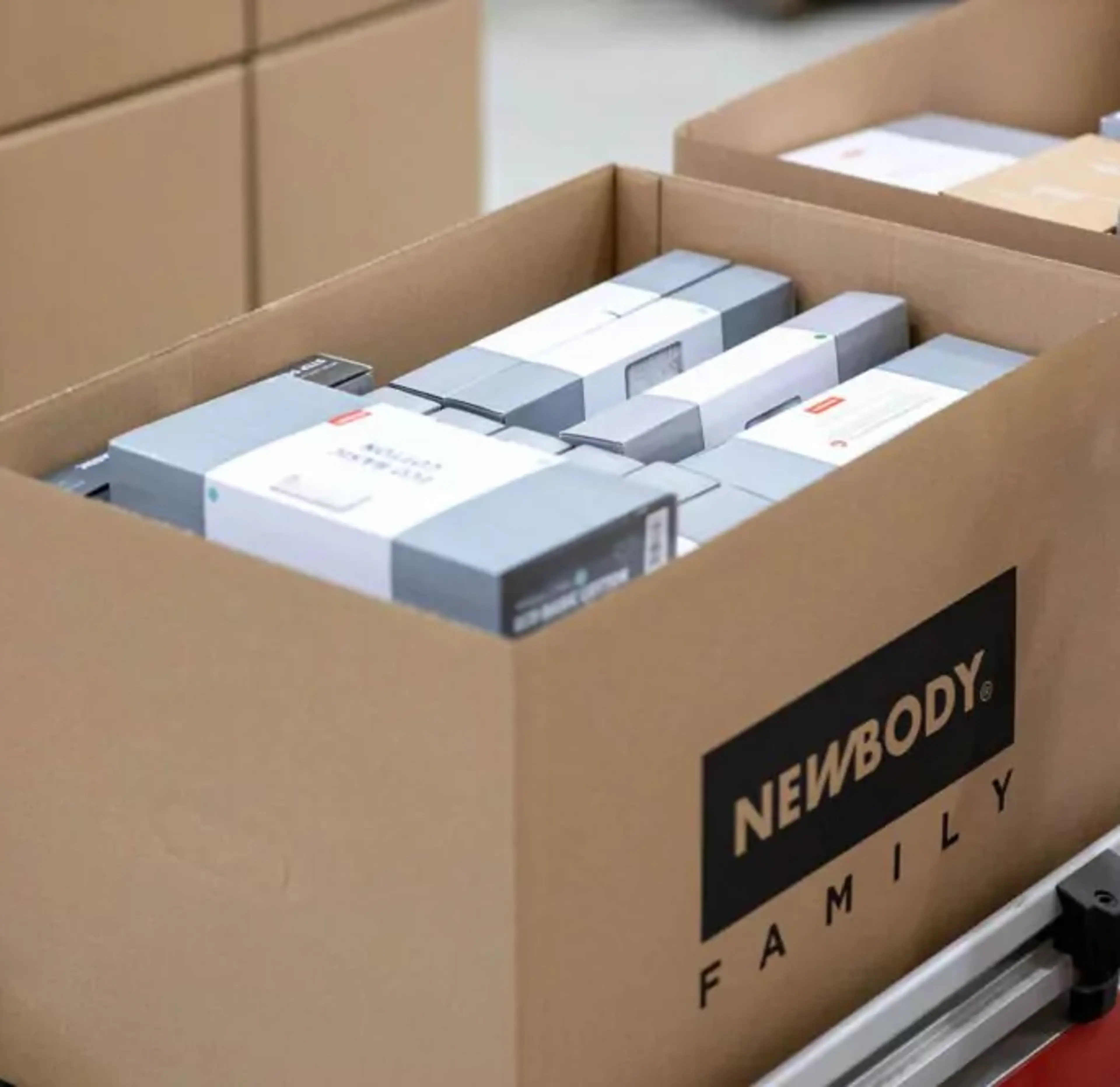 En öppen kartong fylld med prydligt paketerade produkter i olika storlekar, redo för leverans. Kartongen står på en pall tillsammans med andra liknande lådor.