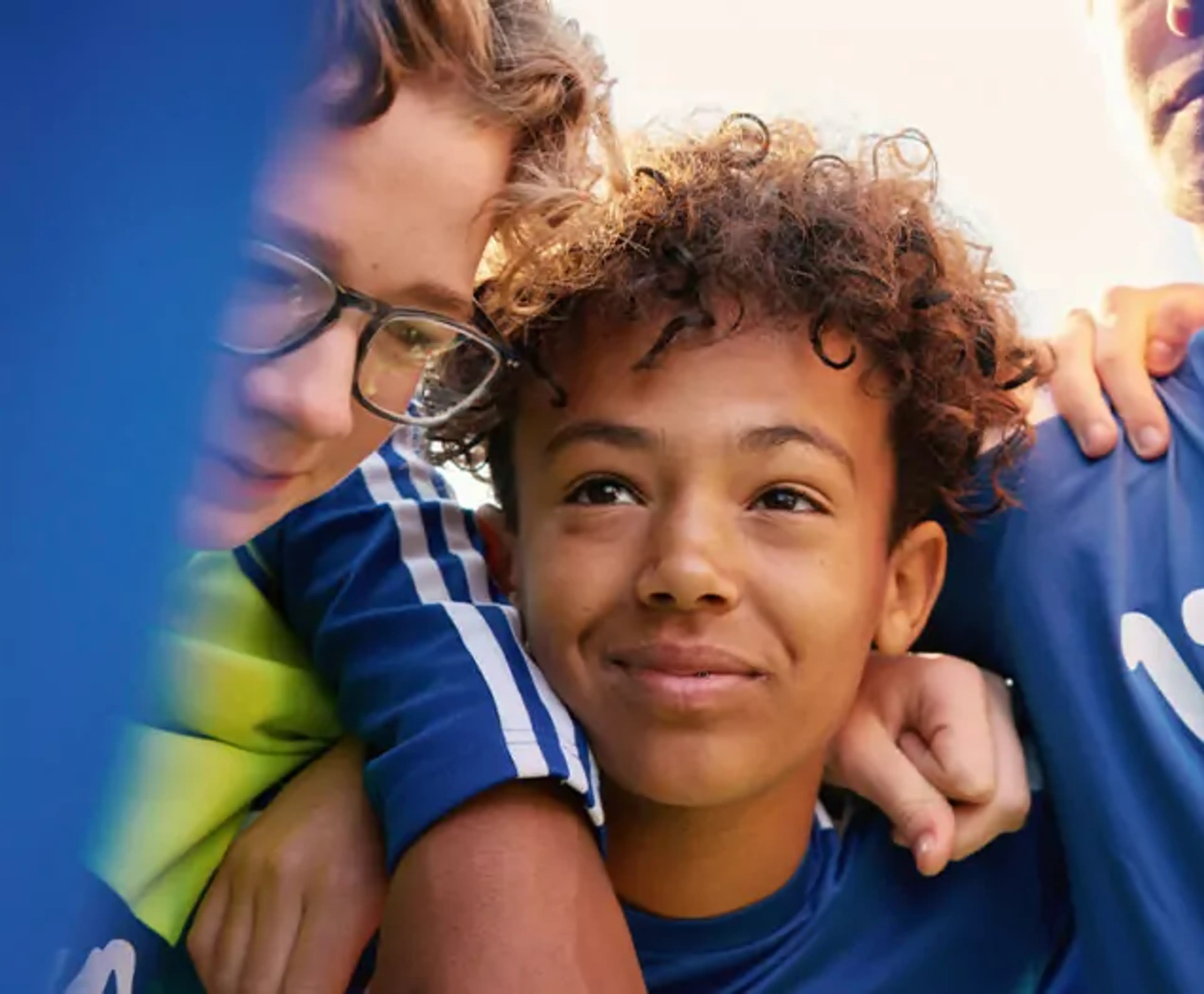 Tre personer i blå tröjor står tätt tillsammans med armarna om varandra. Deras ansikten syns delvis genom ett blått tyg.