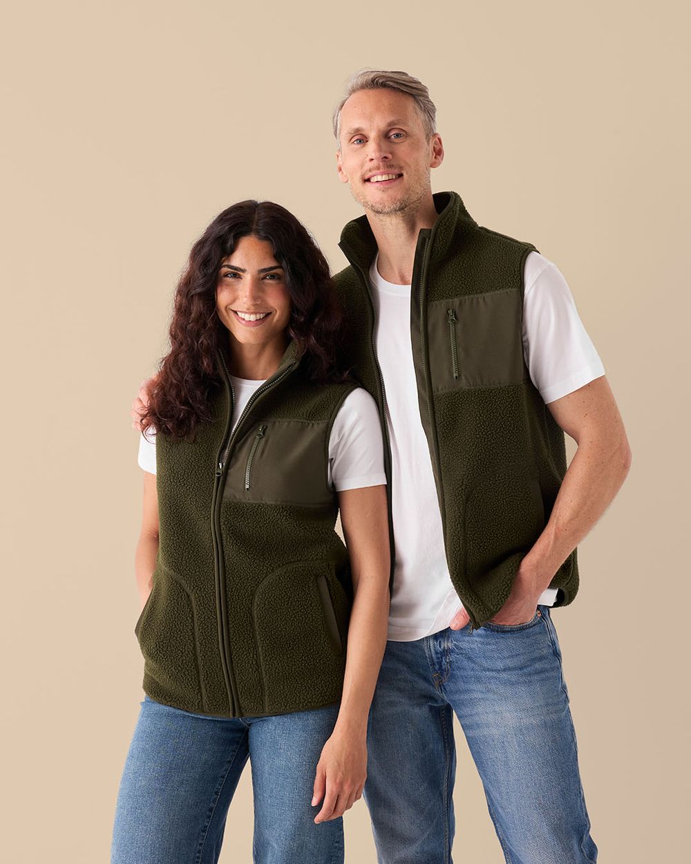 Manlig och kvinnlig modell bär varsin skogsgrön fleeceväst, sedda framifrån.