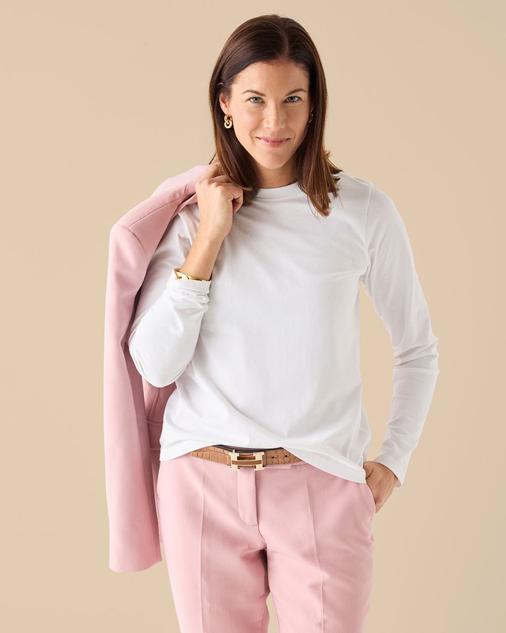 Kvinnlig modell i studiomiljö i long sleeve t-shirt white stylad med rosa kostym.