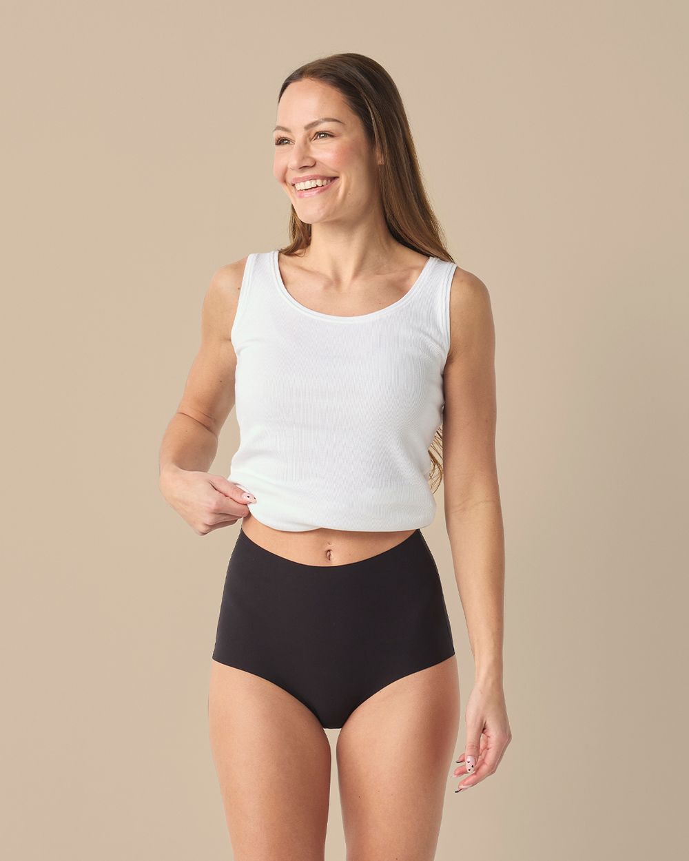 Svarta trosor med hög midja i en mjuk och smidig design. Modellen bär en vit ribbad linne-topp.