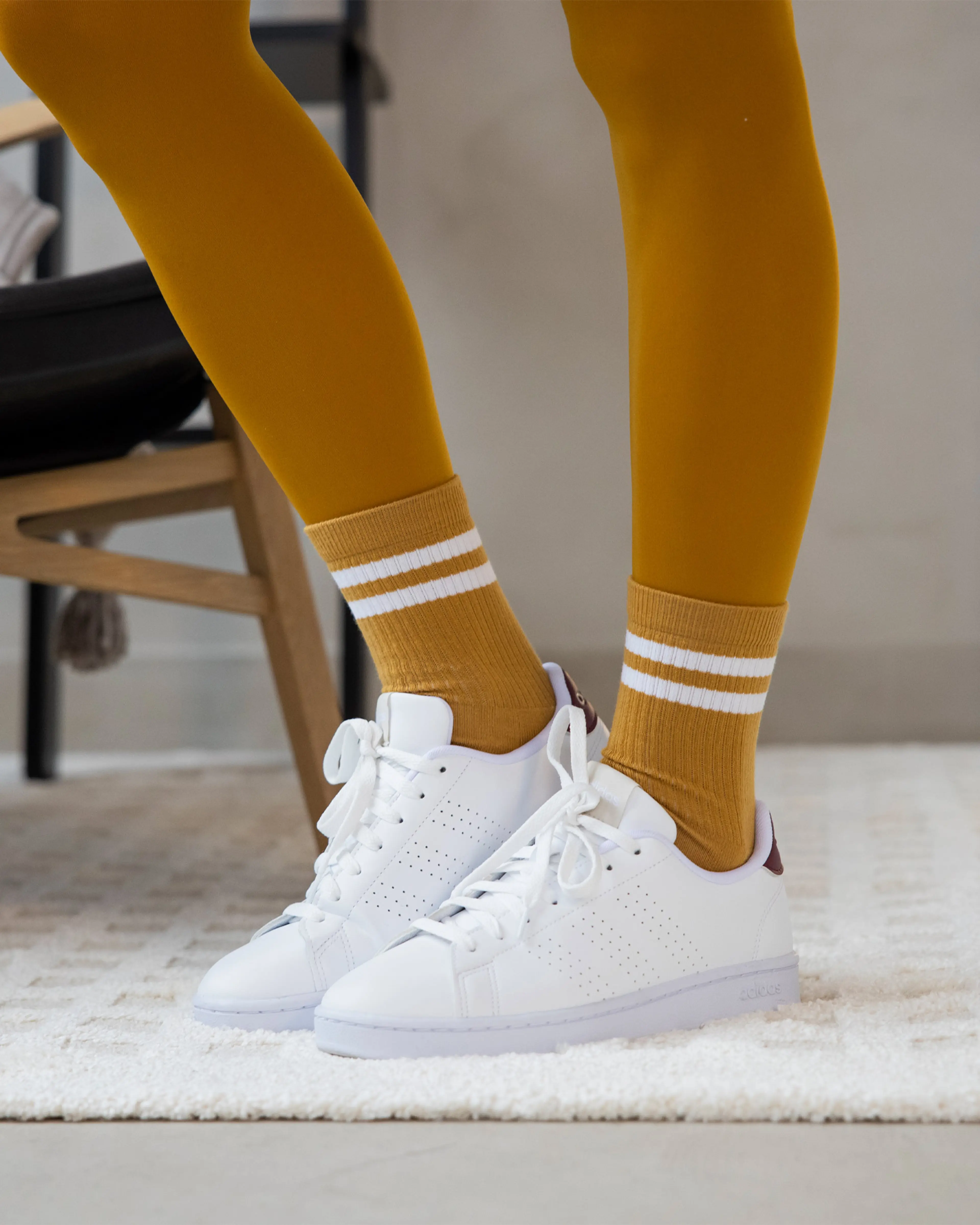 Sportiga, retroinspirerade strumpor i senapsgult med två vita ränder, här matchade med vita sneakers.