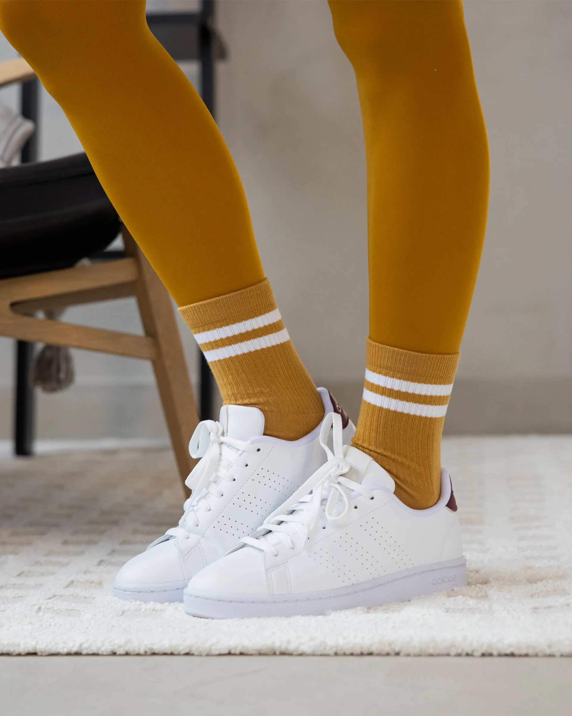 Sportiga, retroinspirerade strumpor i senapsgult med två vita ränder, här matchade med vita sneakers.