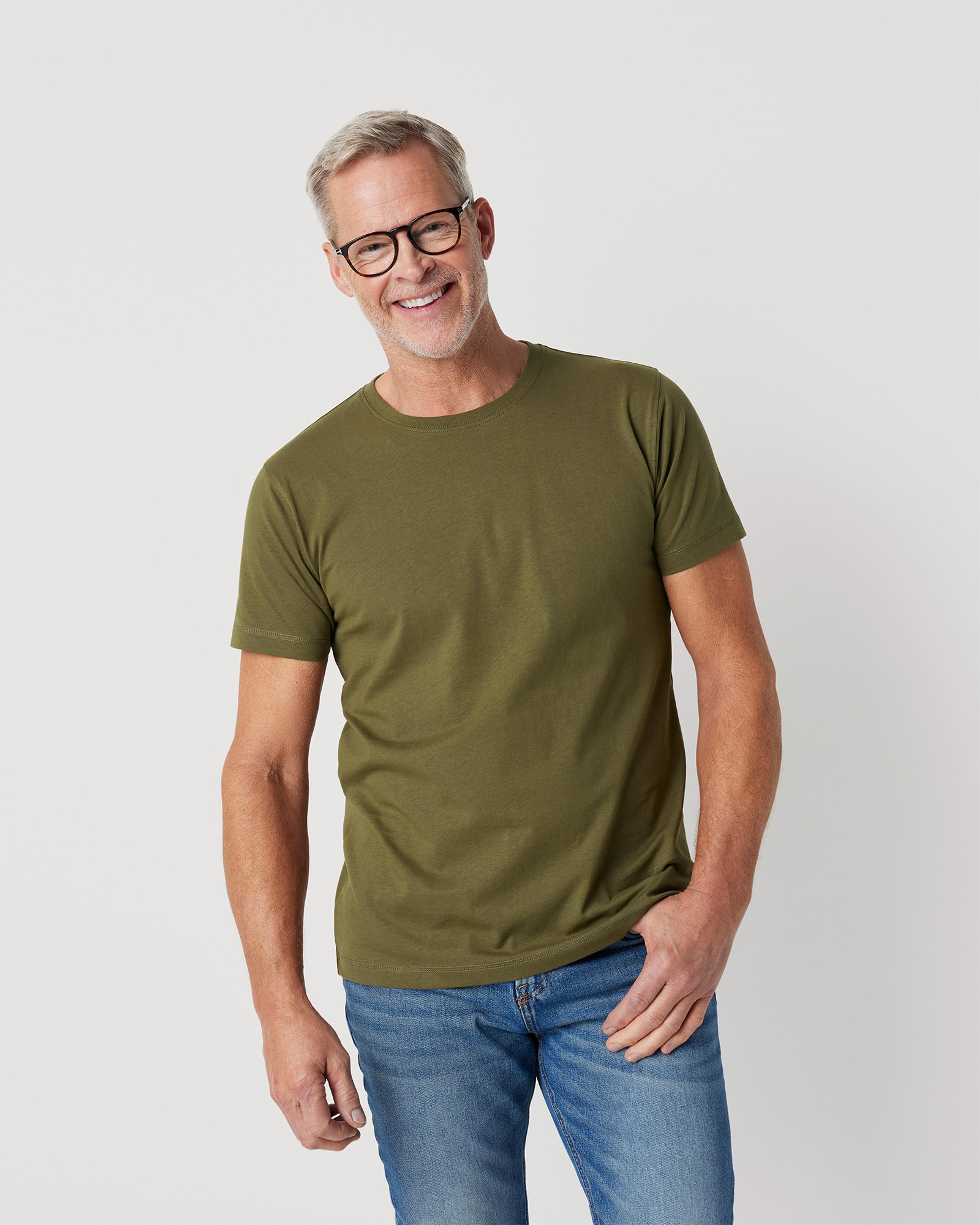 En mjuk, grön t-shirt med rund hals, bärs av en leende man i blå jeans. Tshirten har en enkel och bekväm passform.