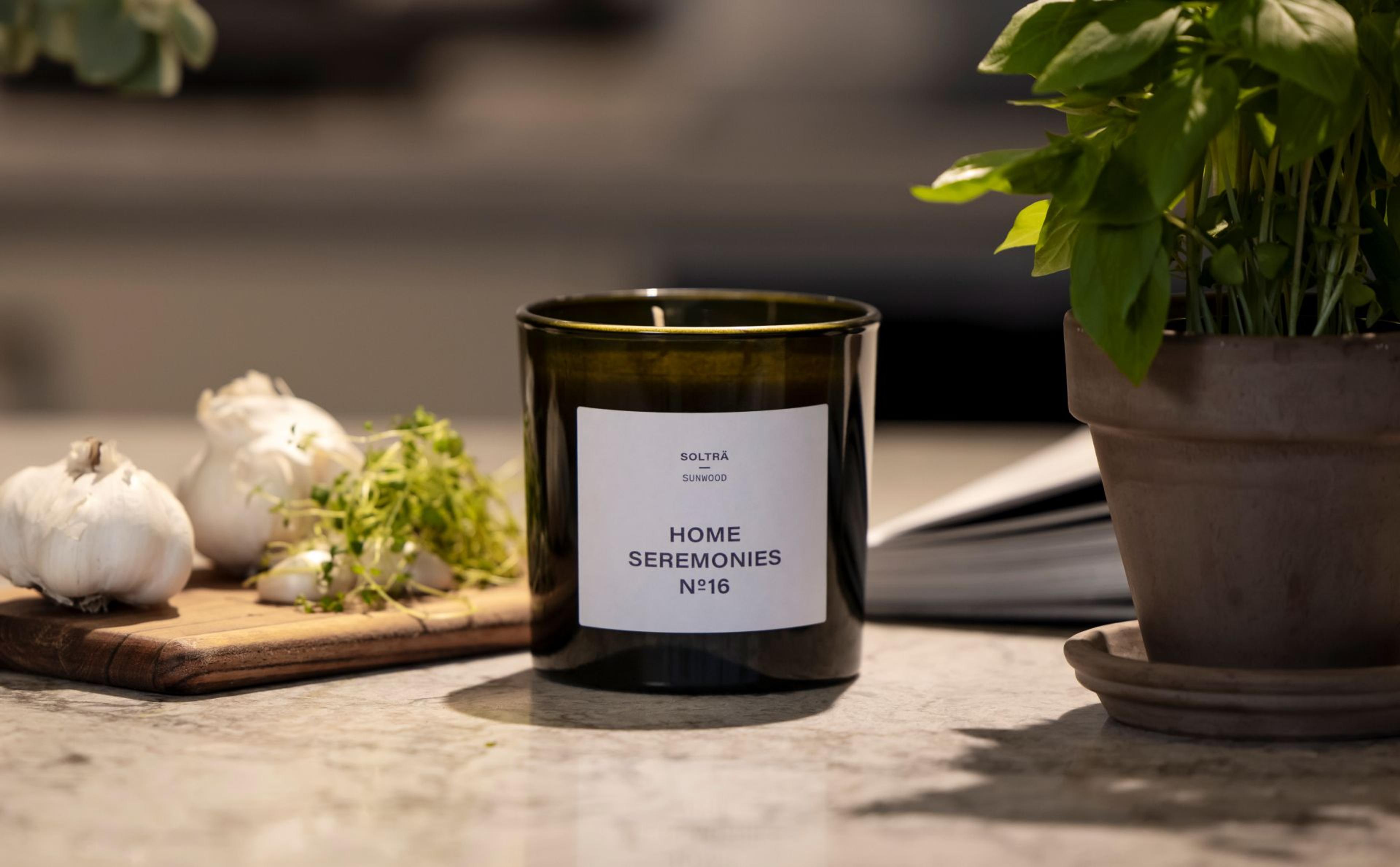 Doftljus står på en köksbänk med vitlök och basilika i bakgrunden