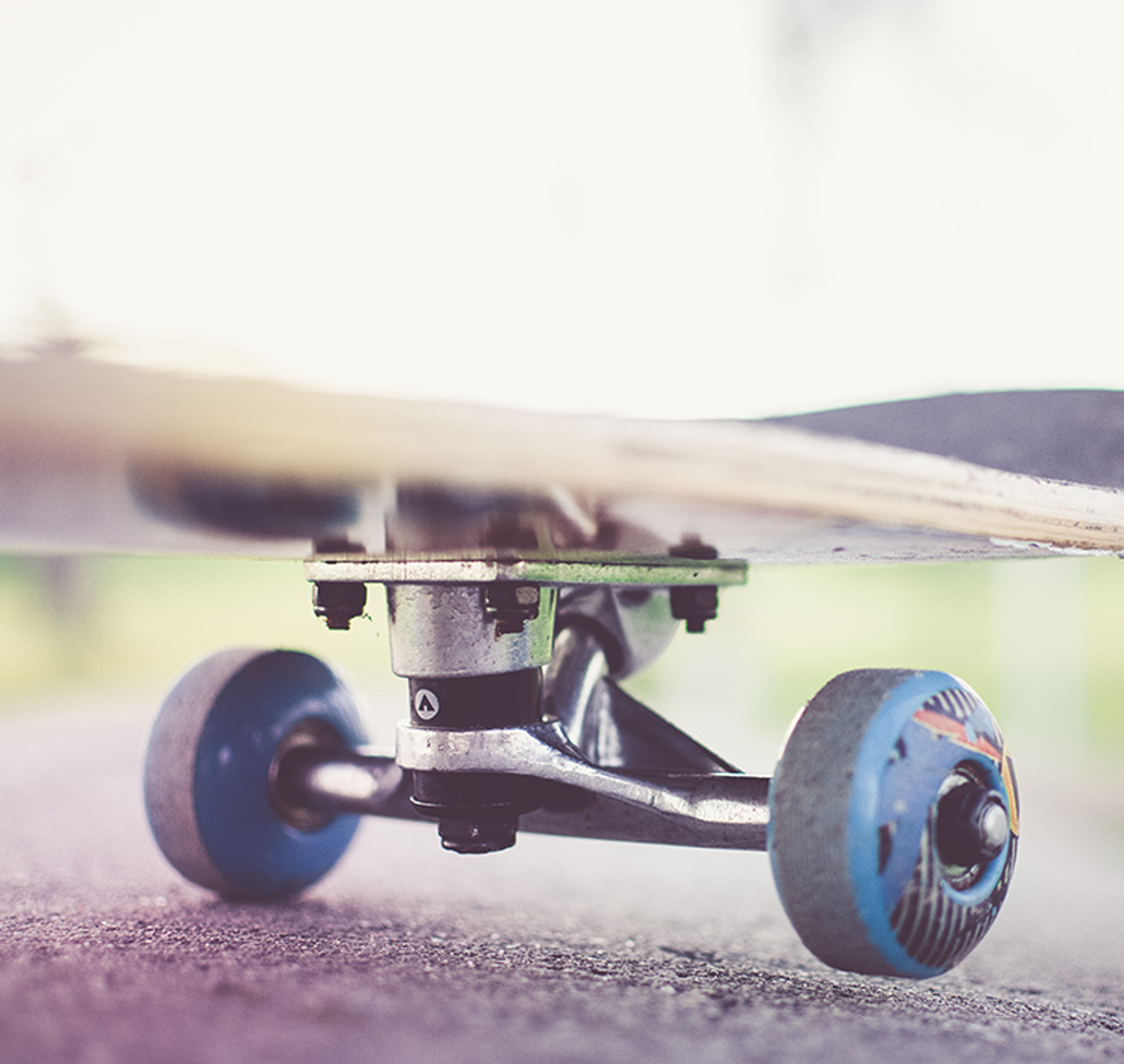 Närbild på en skateboard med blå hjul på asfalt, redo för åkning utomhus.