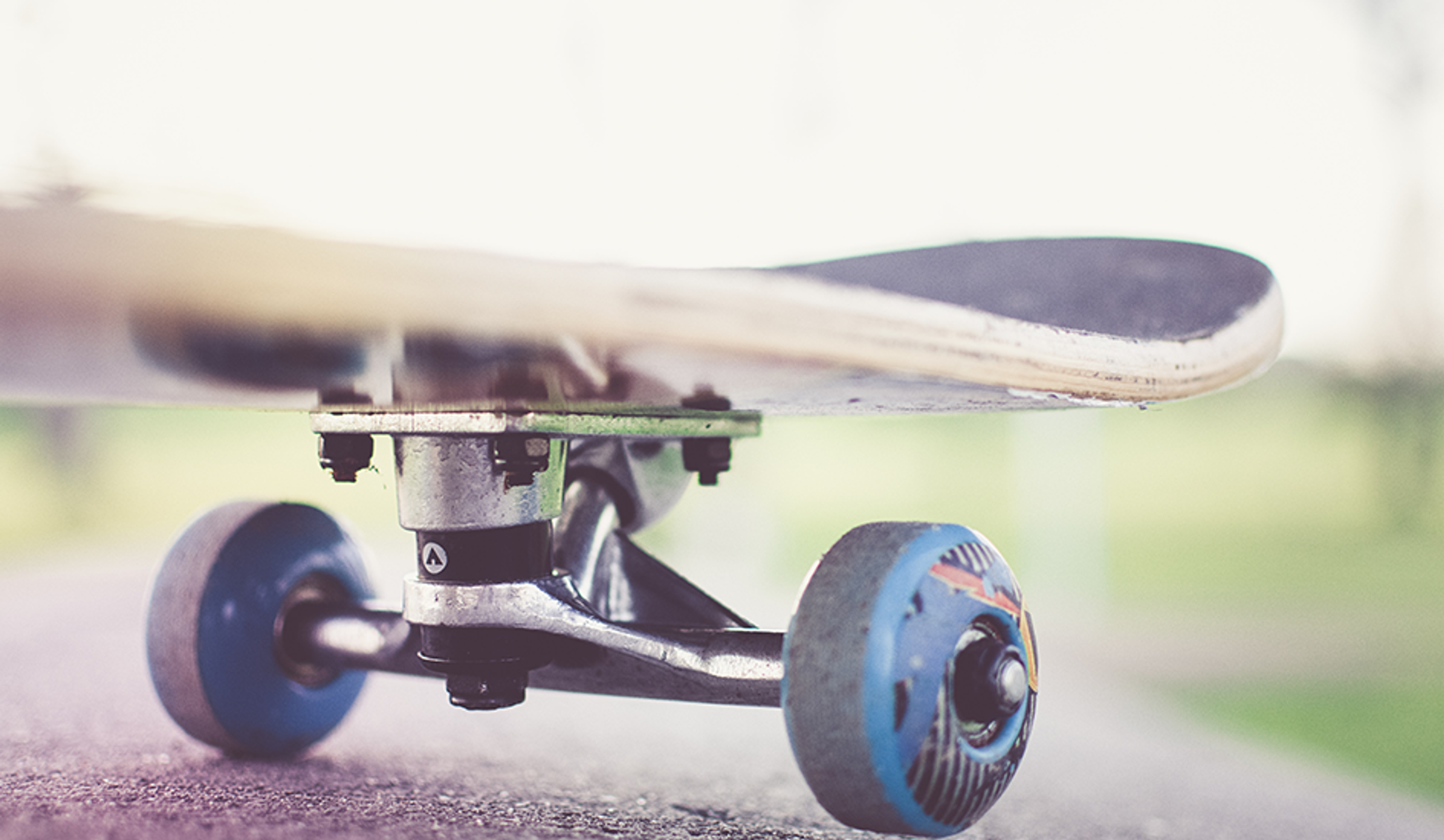 Närbild på en skateboard med blå hjul på asfalt, redo för åkning utomhus.