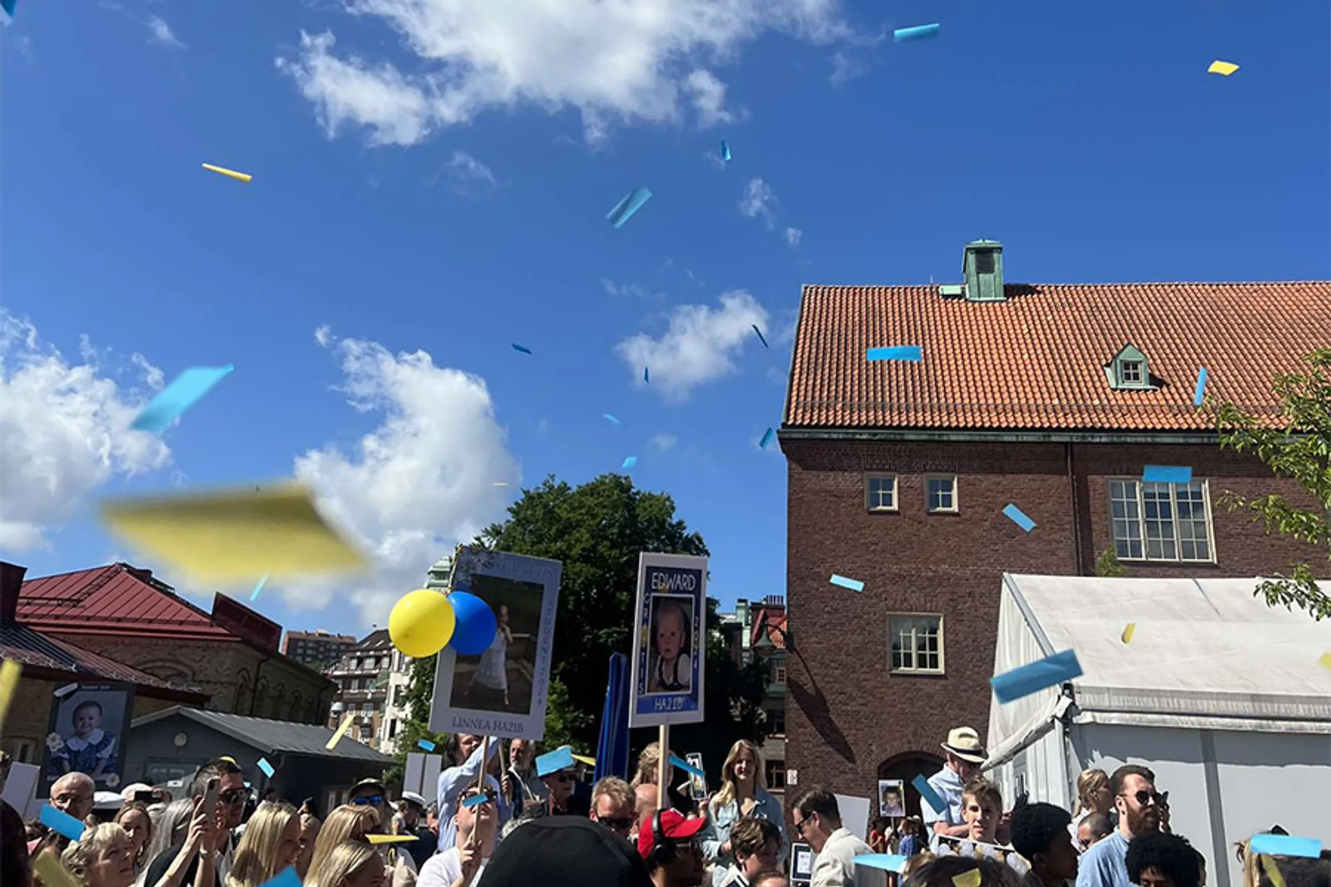 Publik med studentskyltar och konfetti vid studentutspring en solig dag
