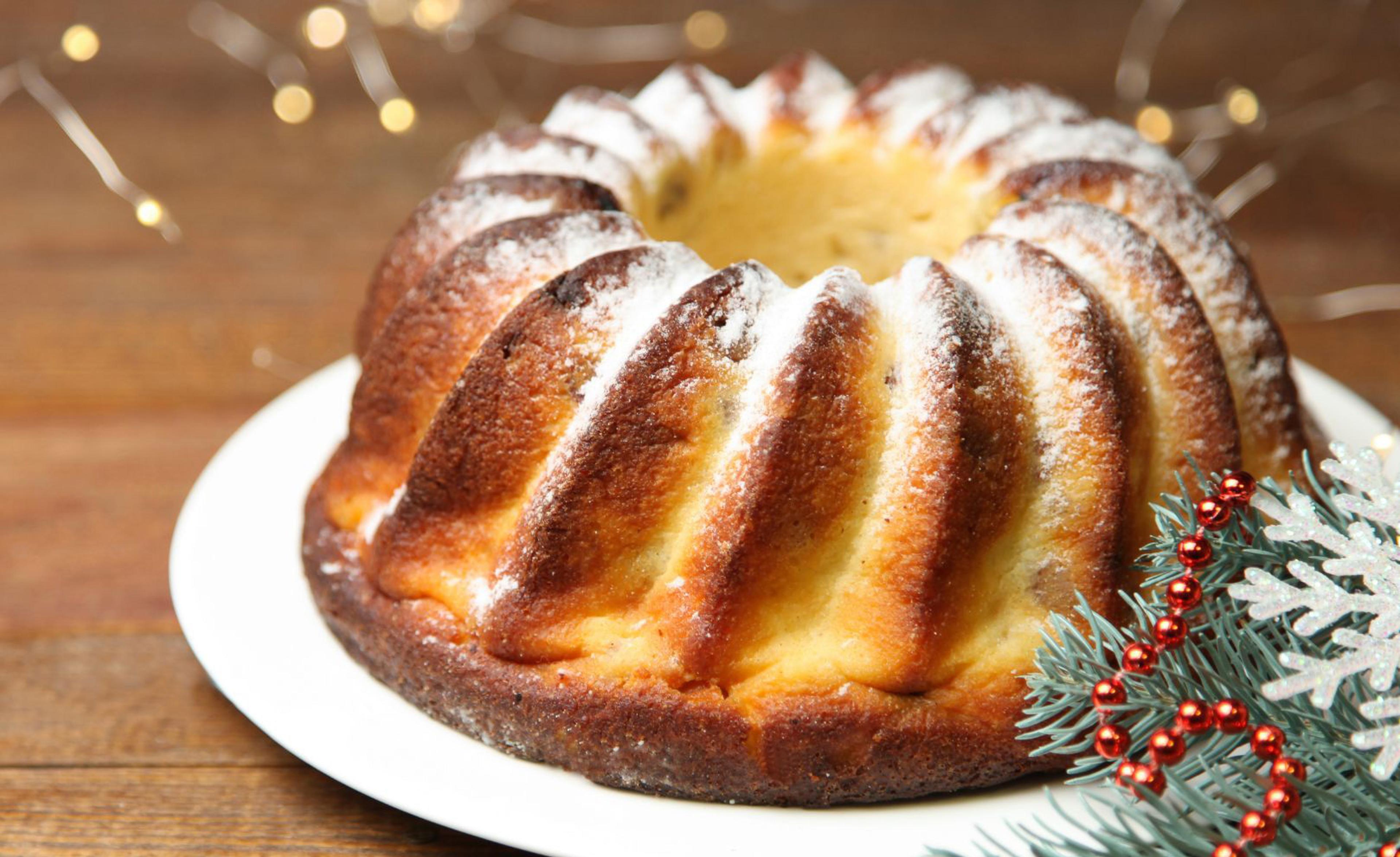En saftig saffranskaka med en gyllene yta, pudrad med florsocker. Dekorerad med granris, röda kulor och en glittrande snöflinga för en julig känsla.