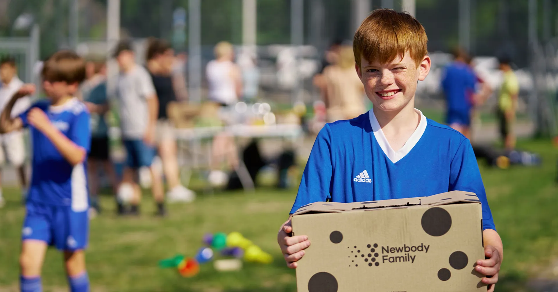 Pojke med paket från Newbody Family på fotbollsplan