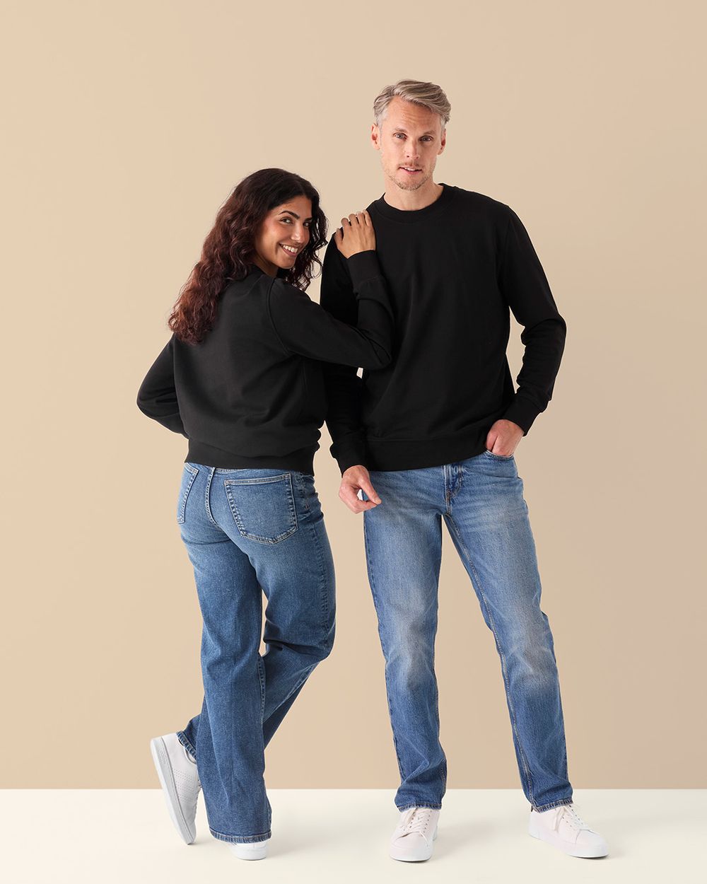 Svart sweatshirt i enkel, klassisk design, modell unisex för både herr och dam. Modellerna bär den tillsammans med jeans och sneakers