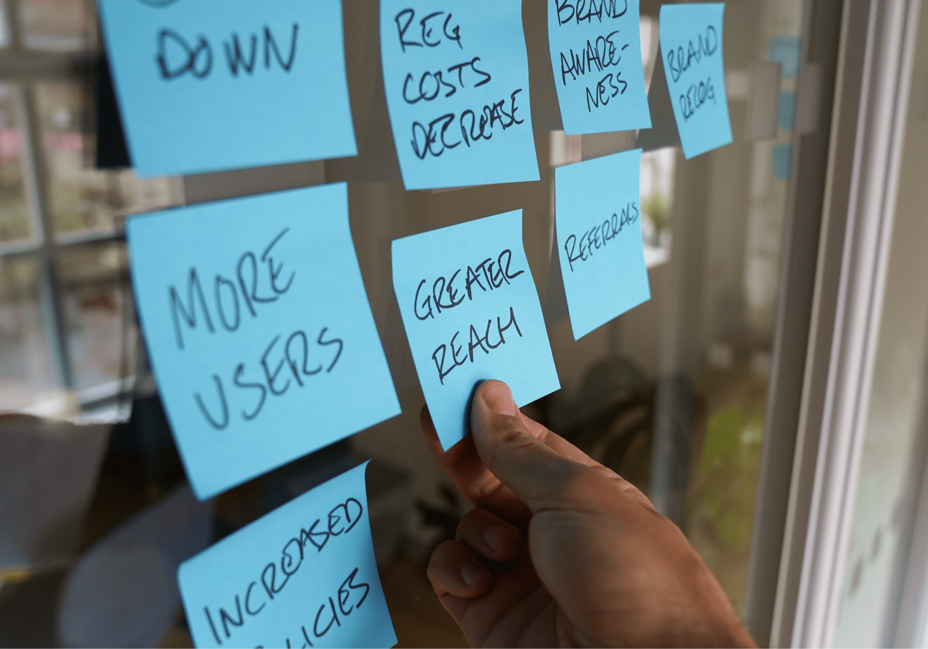 Picture showing a glue design specialist's hand interacting with a wall full of post-it during an in-person workshop with the travel insurance client Wapp