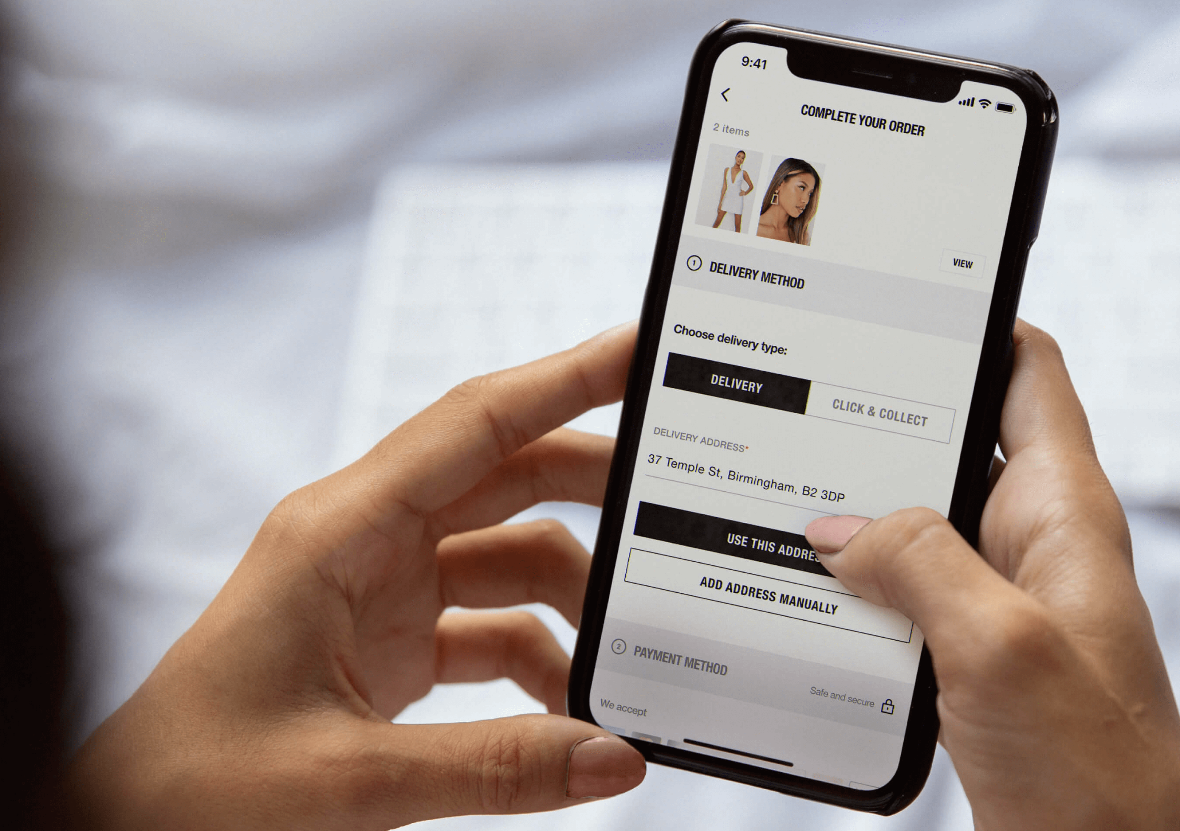 An image of two hands holding a mobile phone which shows the screen where you input your delivery address