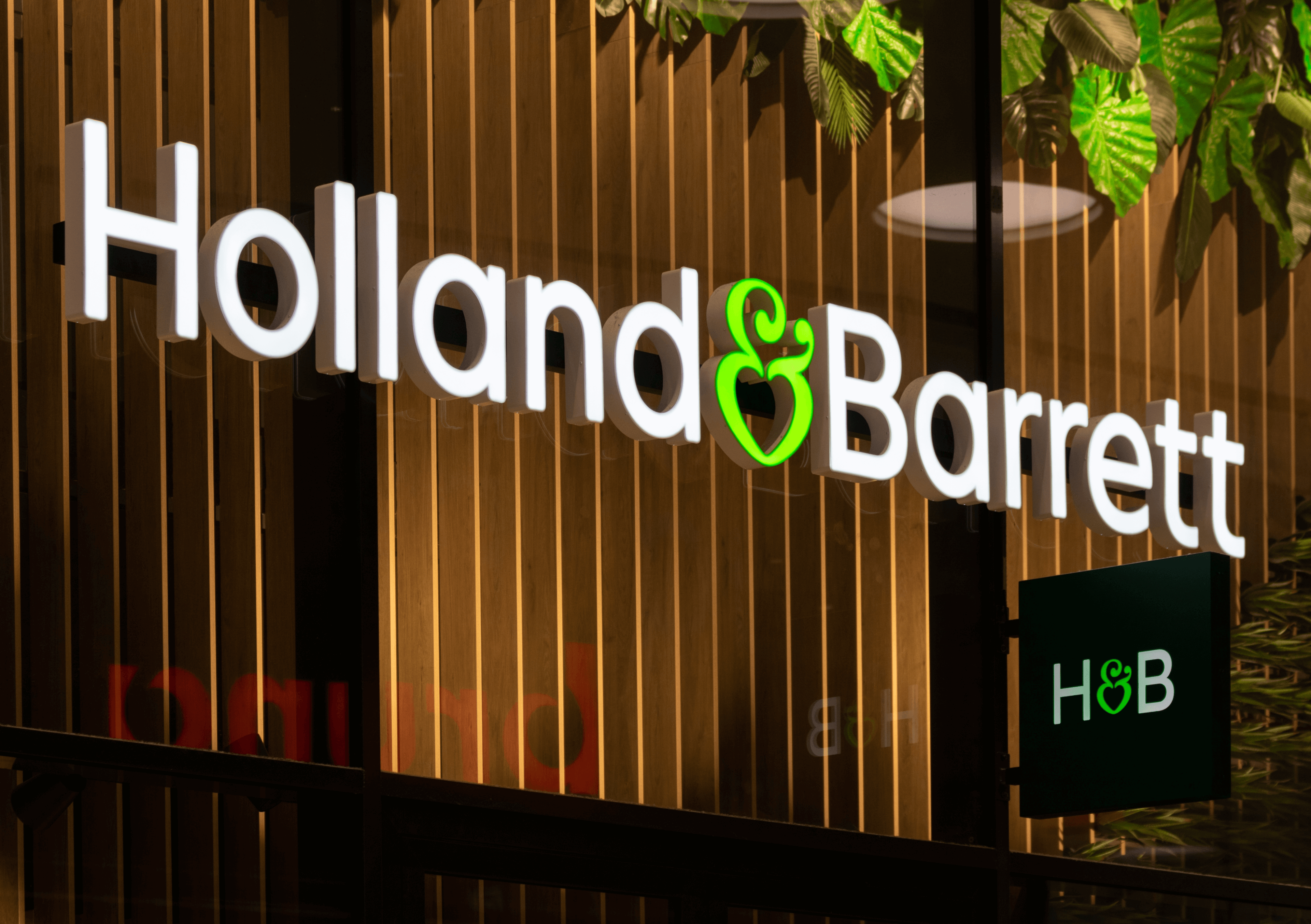 Picture of a Holland&Barrett store at night. The logo is well lit up and visible.