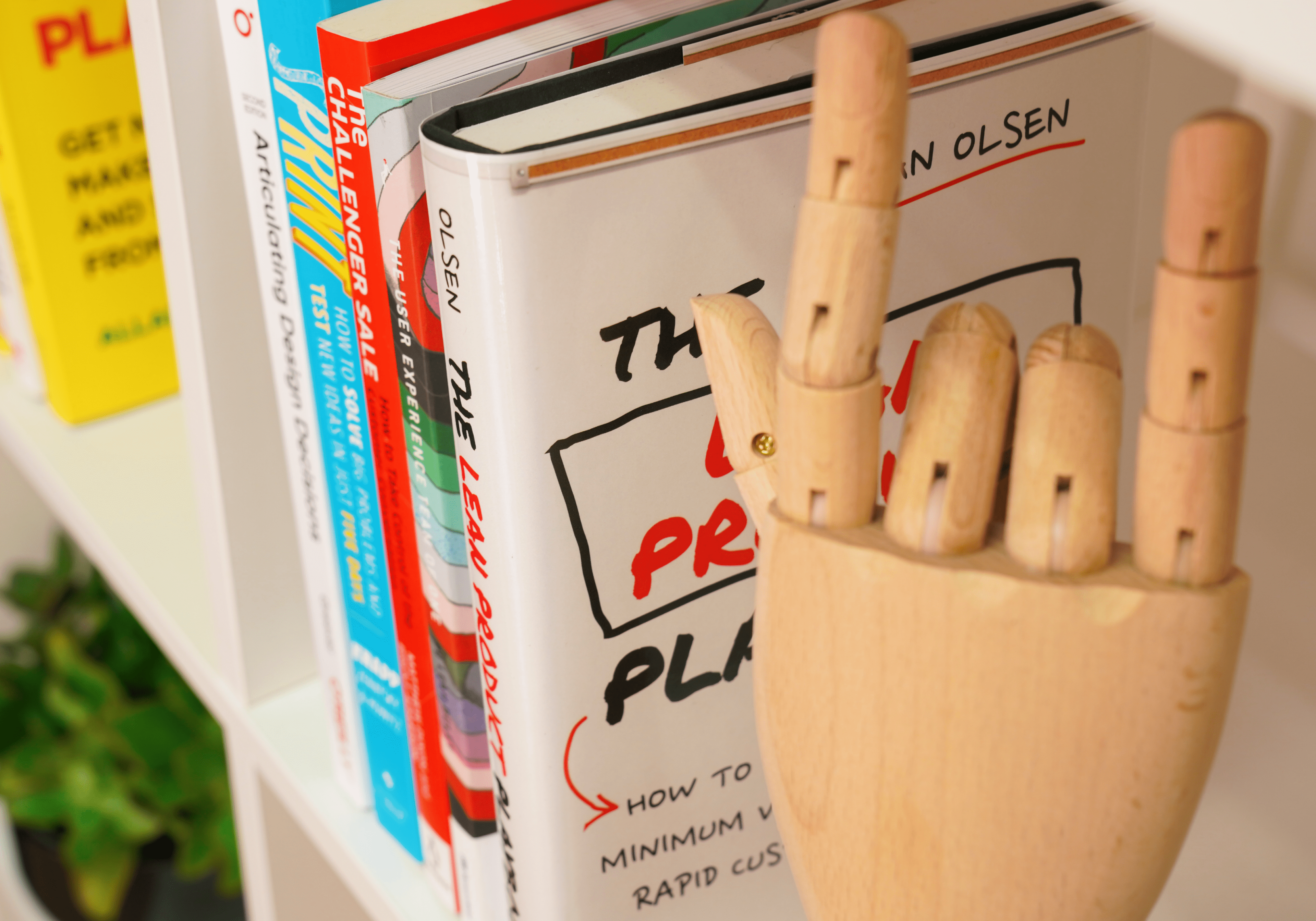 Picture of design-related books and a wooden mannequin hand sitting on a shelf at the Design Studio Glue office