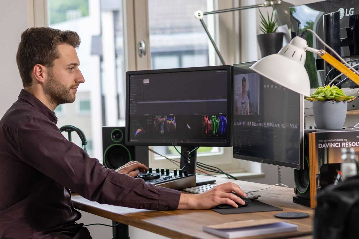 Mann sitzt an PC und schneidet videos auf zwei bilschrimen