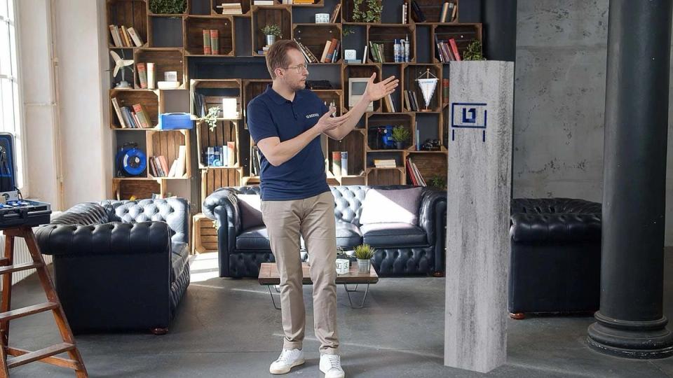 Referent präsentiert in einem gestalteten Set mit Regalwand und Requisiten