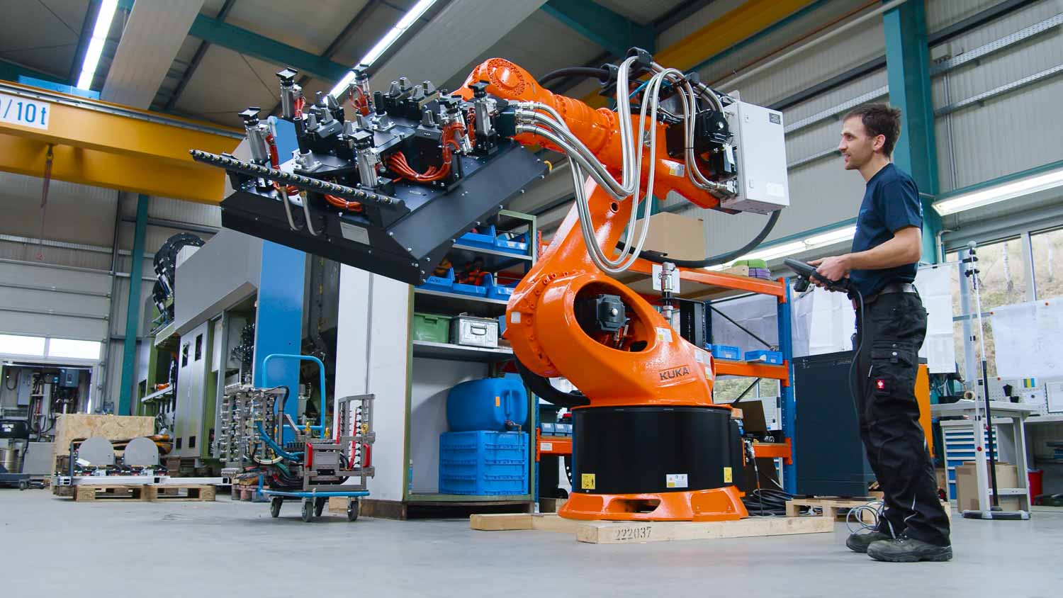 Still aus dem Böhmer-Imagefilm: Mitarbeiter steuert einen orangefarbenen KUKA-Roboterarm in der Halle